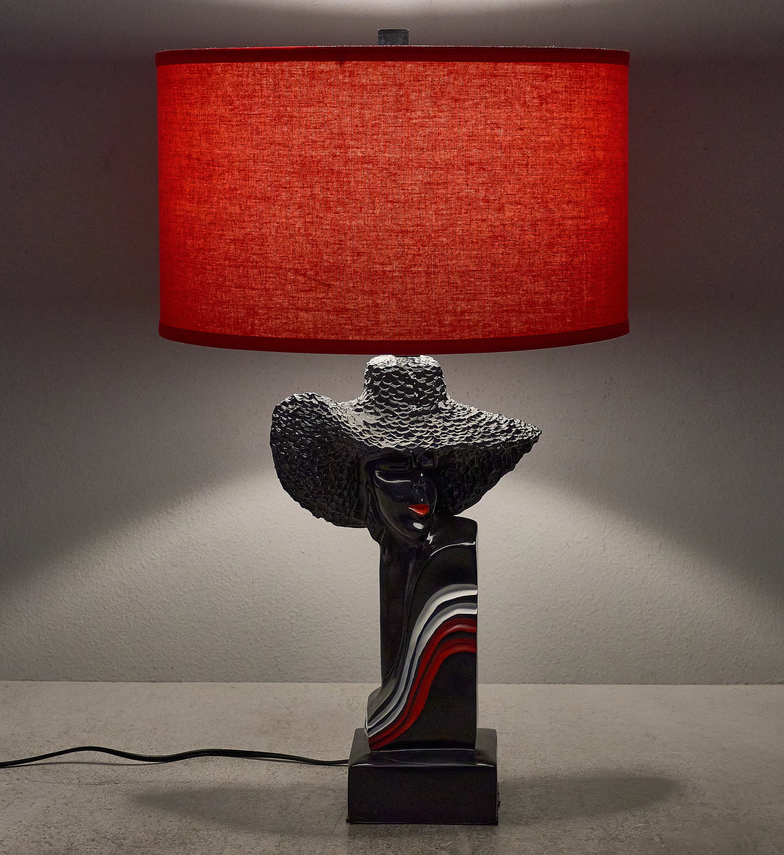 Barsony Figural Lady Lamp: Barsony table lamp depicting bust of a woman wearing a wide-brimmed hat, with red and white accents on the base, topped with red fabric shade height 27 in. x diameter 15 in. Provenance: Property from