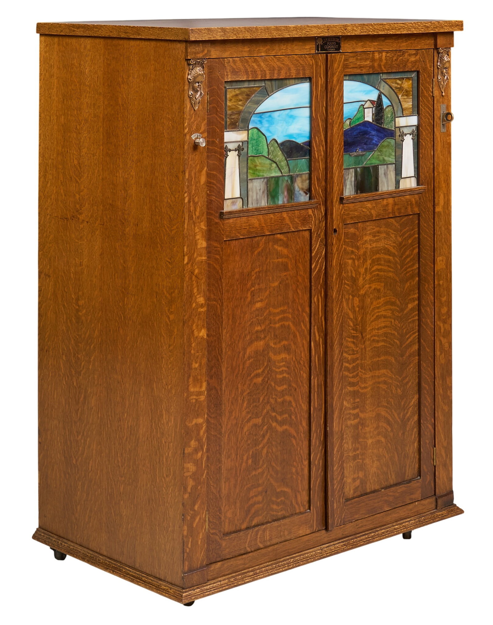 J.P. Seeburg Piano Co. Player Piano with Music Rolls: J.P. Seeburg Piano Co. player piano with wooden cabinet with stained glass panels depicting a landscape, intricate interior mechanism, circa early 20th century, in working condition, includes key