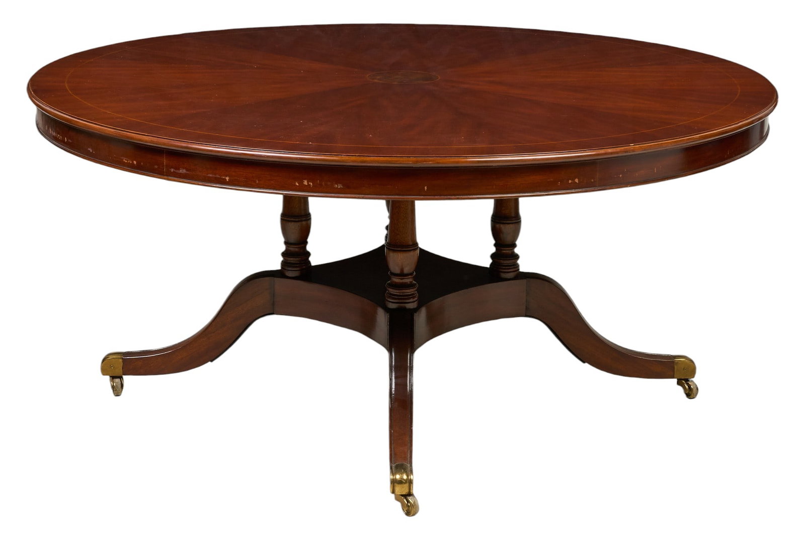 Circular Dining Table: Circular dining table on pedestal base with four splayed legs, each ending in brass casters height 29.5 in. x diameter 65 in. Proven