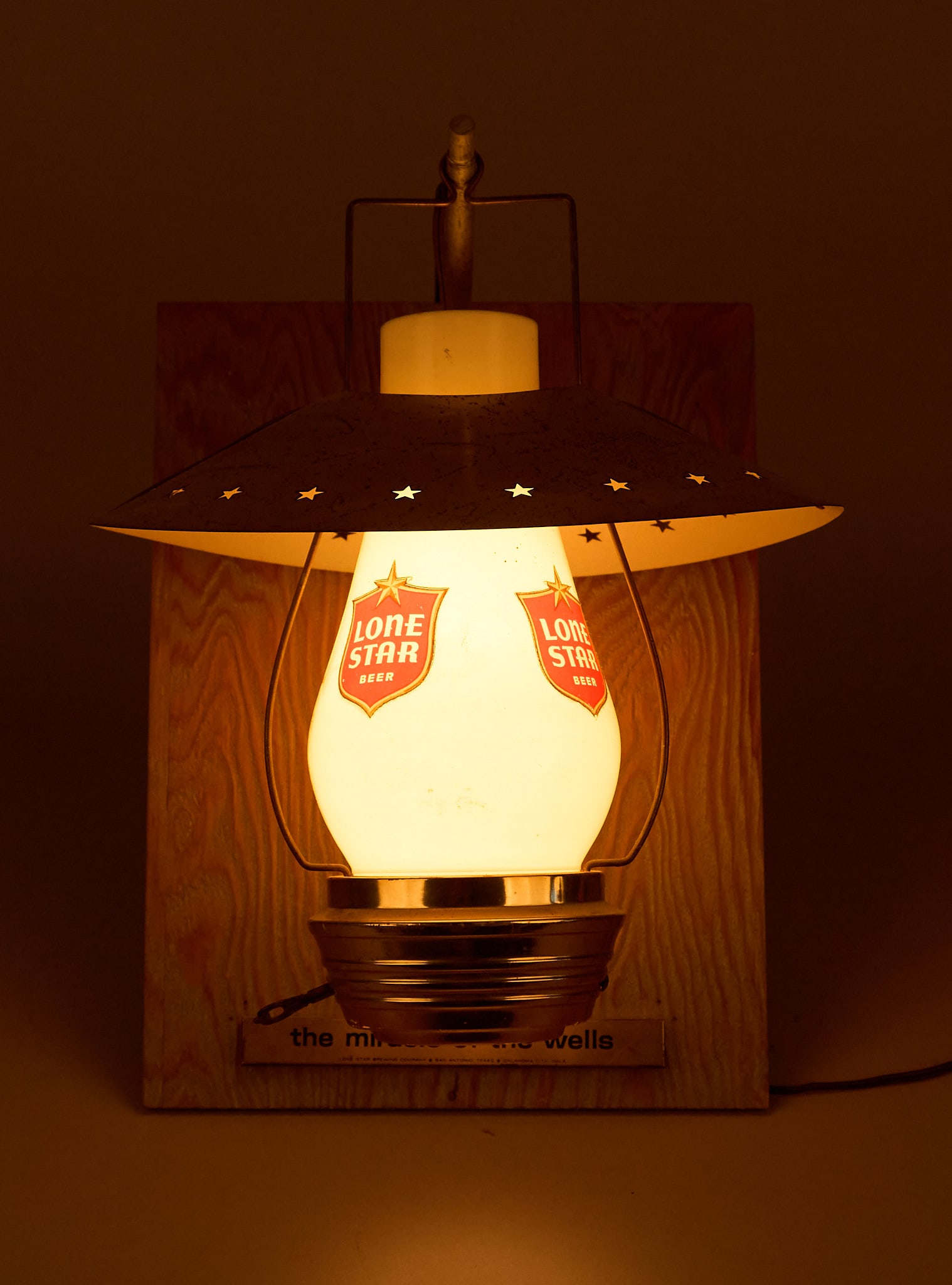 Lone Star Beer Lighted Lantern: Lone Star Beer lighted lantern attached to wooden plaque, with star-stamped metal shade height 16 in. x width 12 in. x depth 12 in. Provenance: Property from the collection of Linda Muth, 
