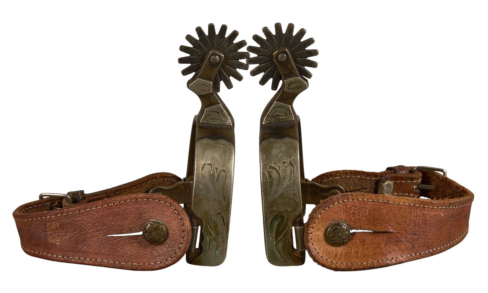 Pair of Vintage McChesney Marked Spurs: Pair of McChesney cowboy spurs, marked on heels strap near button, leather heel straps, silver overlay, and flower motif buttons heel width: 3 in. overall length: 6 in. rowel diameter: 1.75 