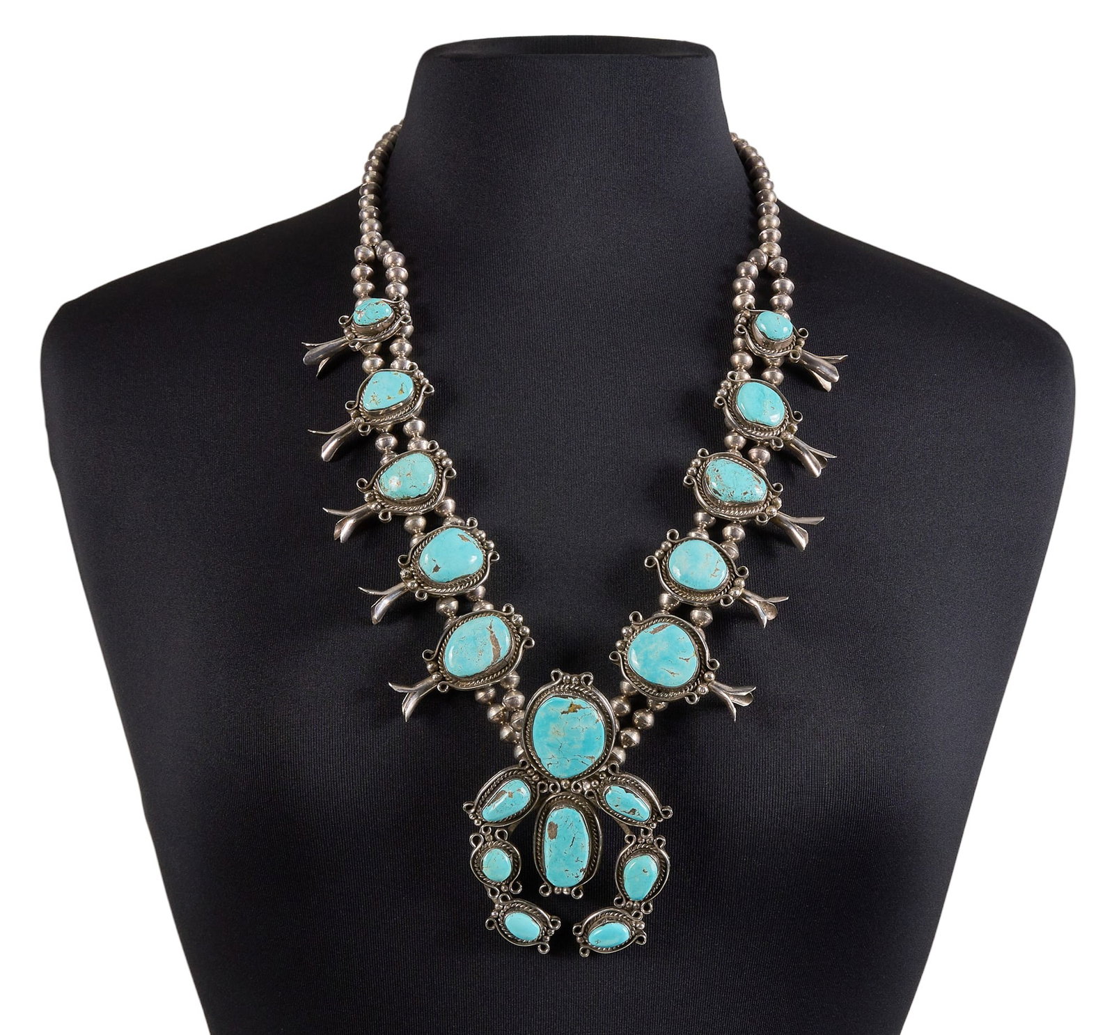 Vintage Sterling Silver & Turquoise Squash Blossom: Vintage sterling silver squash blossom necklace, set with large turquoise cabochons, featuring twisted rope motifs and scrolled elements, with hook and eye closure Length: 29 in. Total weight: 58.9 g 