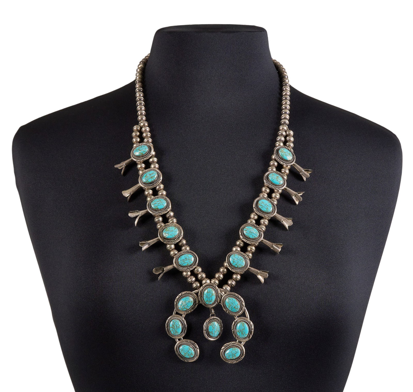 Sterling Silver & Turquoise Squash Blossom: Sterling silver squash blossom necklace, set with turquoise cabochons and twisted rope motifs, with hook and eye closure Length: 28 in. Total weight: 123.6 g Provenance: Property from a home in