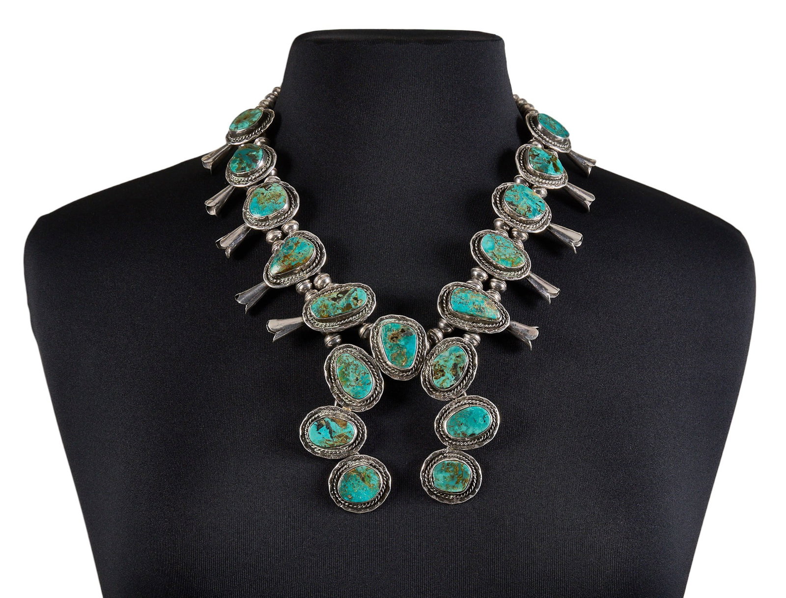 Sterling Silver & Turquoise Squash Blossom: Sterling silver squash blossom necklace, set with turquoise in twisted rope style bezel settings, with hook and eye closure Length: 22 in. Total weight: 178.9 g