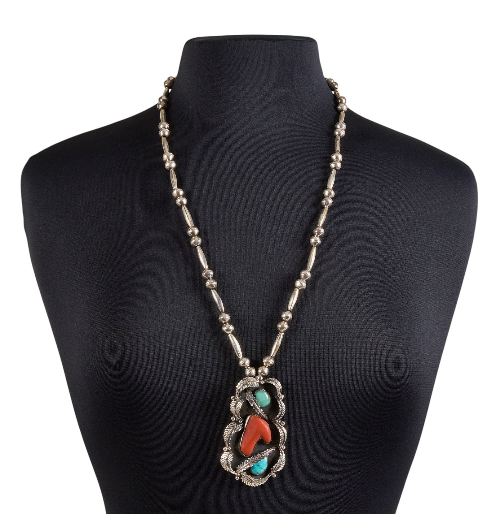 Turquoise & Coral Pendant Necklace: Sterling silver pendant necklace, on an old Navajo chain, with newer pendant set with turquoise and coral, featuring feather motifs Length: 29 in. Total weight: 62.5 g Provenance: Property from a