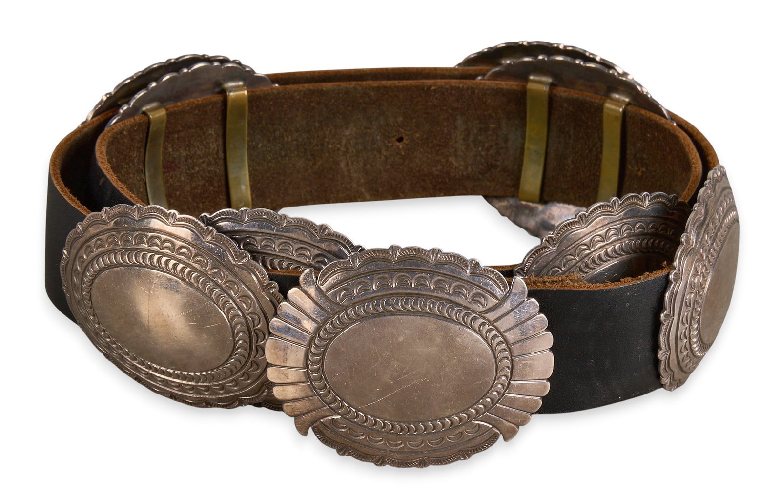 L&M Nez, Navajo Sterling Concho Belt: Leonard and Marian Nez, Navajo sterling silver concho belt, with eight conchos and buckle on black leather belt, marked to buckle Length: 42 in. Total weight: 531.1 g Provenance: Property from a home 