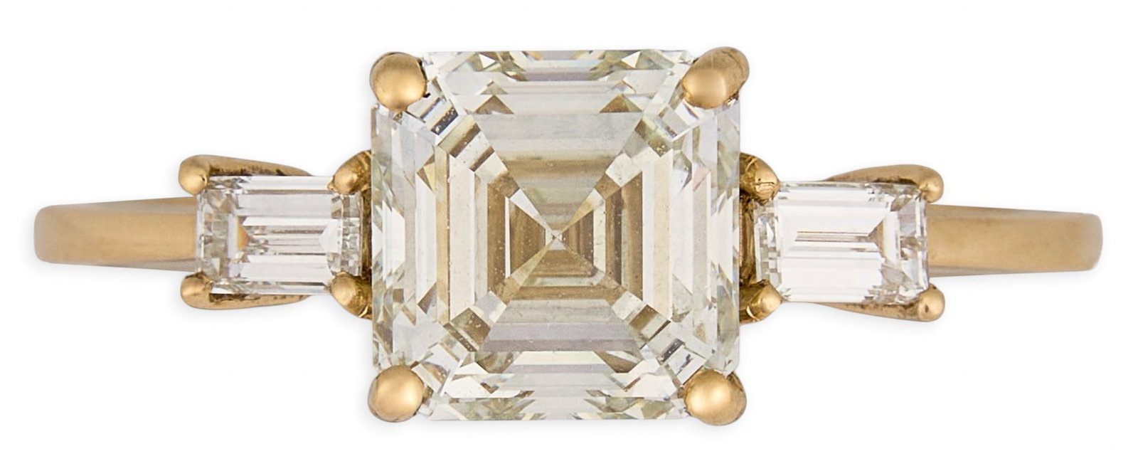 18K Asscher Cut Diamond Ring: 18K yellow gold ring centered an Asscher cut diamond, approximately 1.7 ct, graded K color and VVS2 clarity, flanked by baguette cut diamonds, approximately 0.24 ctw, central diamond