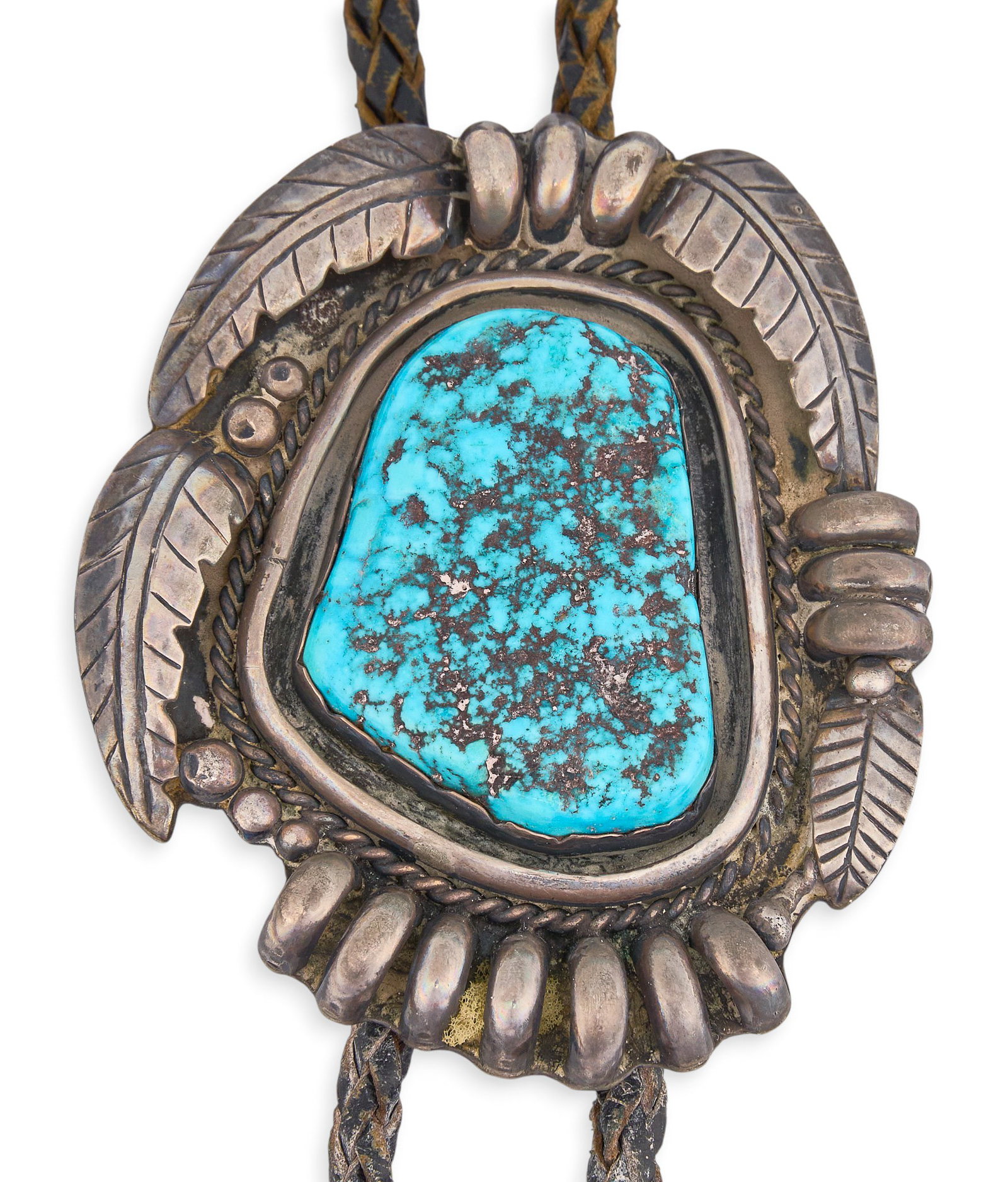 Red McCombs | Sterling Silver & Turquoise Bolo Tie: Sterling silver bolo tie set with large turquoise stone, in a shadowbox style setting, accented by twisted wire and applied foliate motifs, on a braided black leather cord ending in turquoise-set aigu