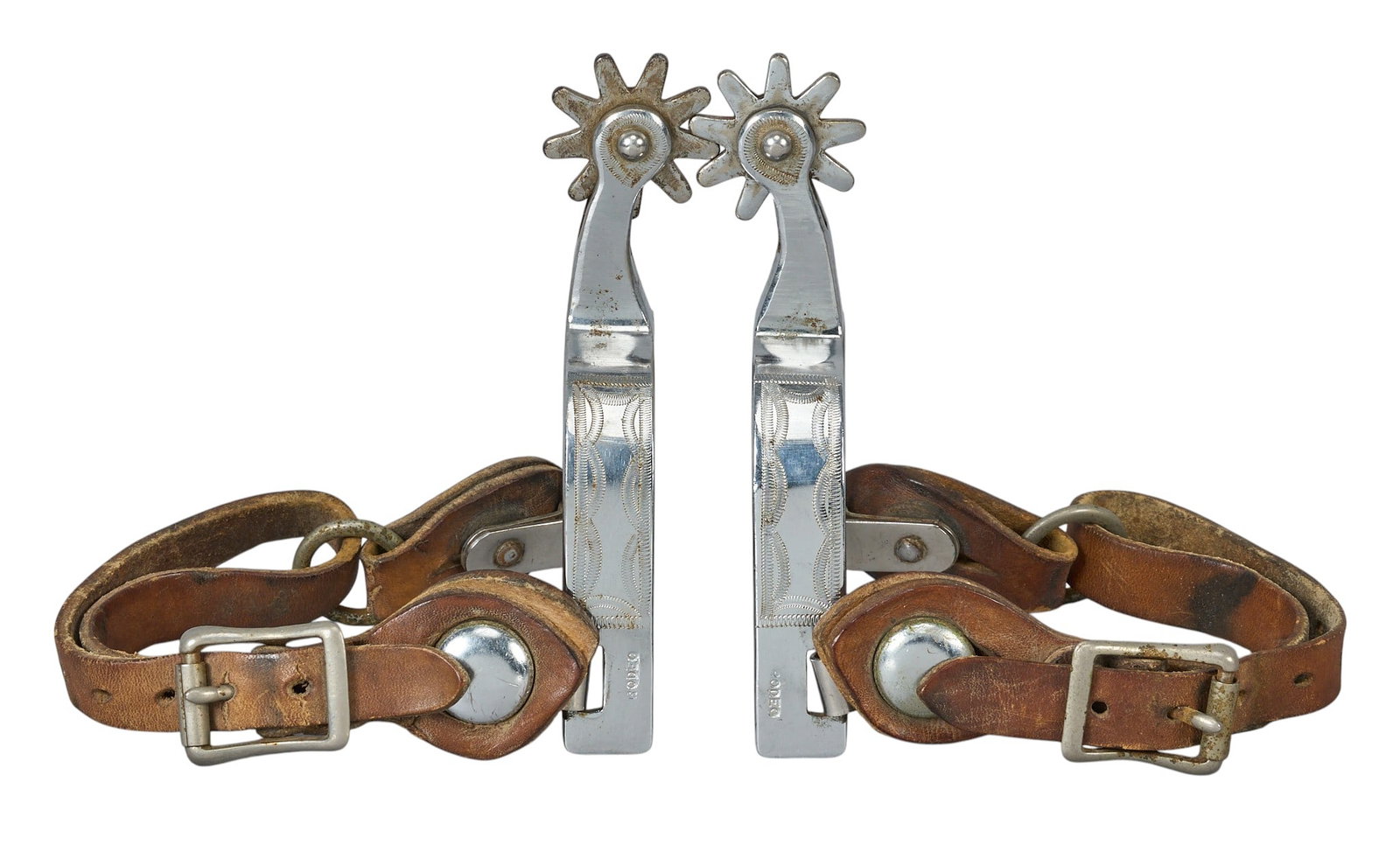 Red McCombs | Pair of Contemporary Rodeo Spurs: Pair of engraved contemporary "Rodeo" spurs with leather heel straps overall length: 5.5 in. heel width: 3.375 in. rowel diameter: 1.5 in. 