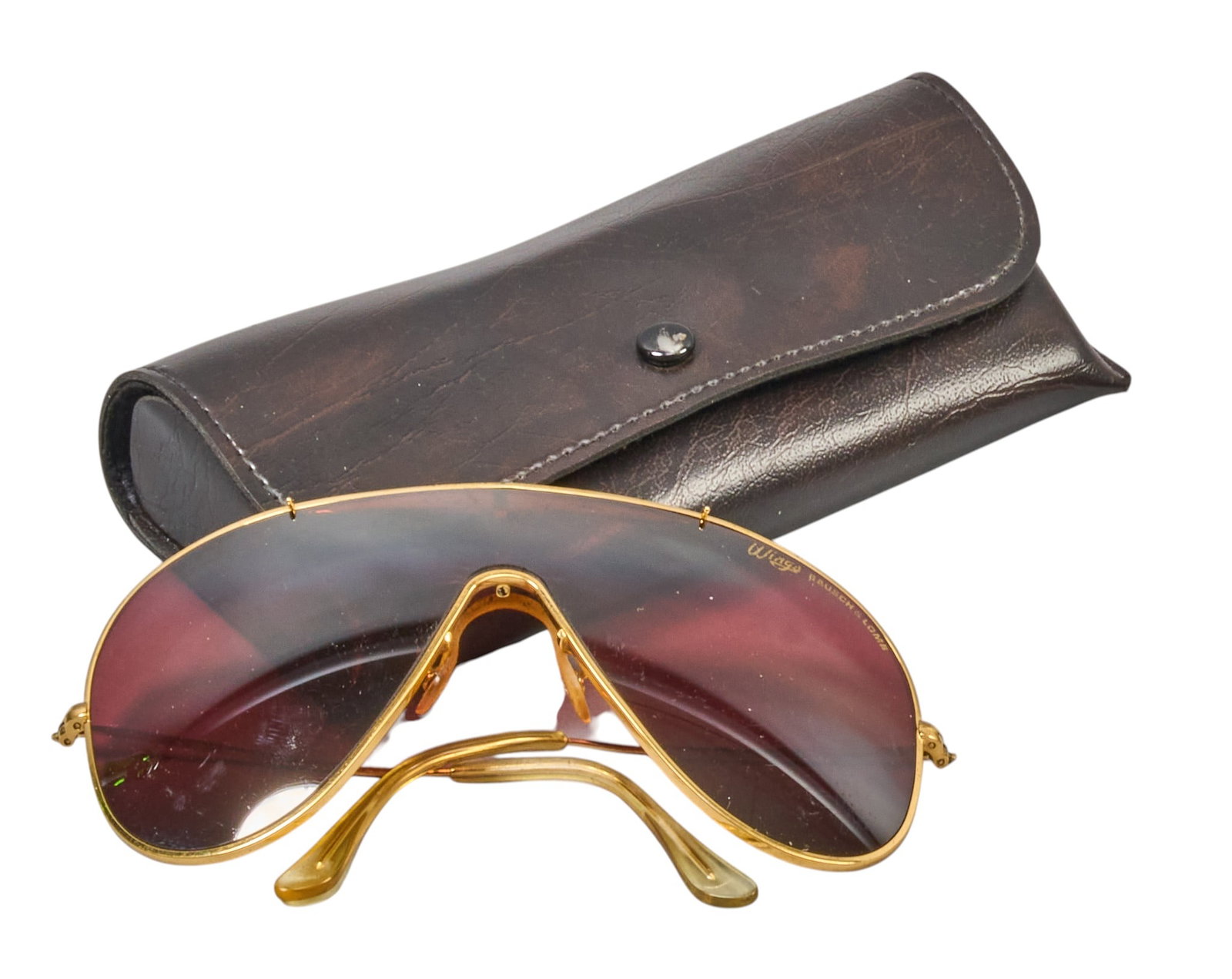 Red McCombs | Vintage Bauch & Lomb x Ray-Ban Wings Sunglasses: Vintage pair of Ray-Ban Wings sunglasses by Bausch & Lomb featuring golden metal frame and bronze-colored lenses, includes black leather case ~150 mm Temple Length length 7 in. x width 3 in.