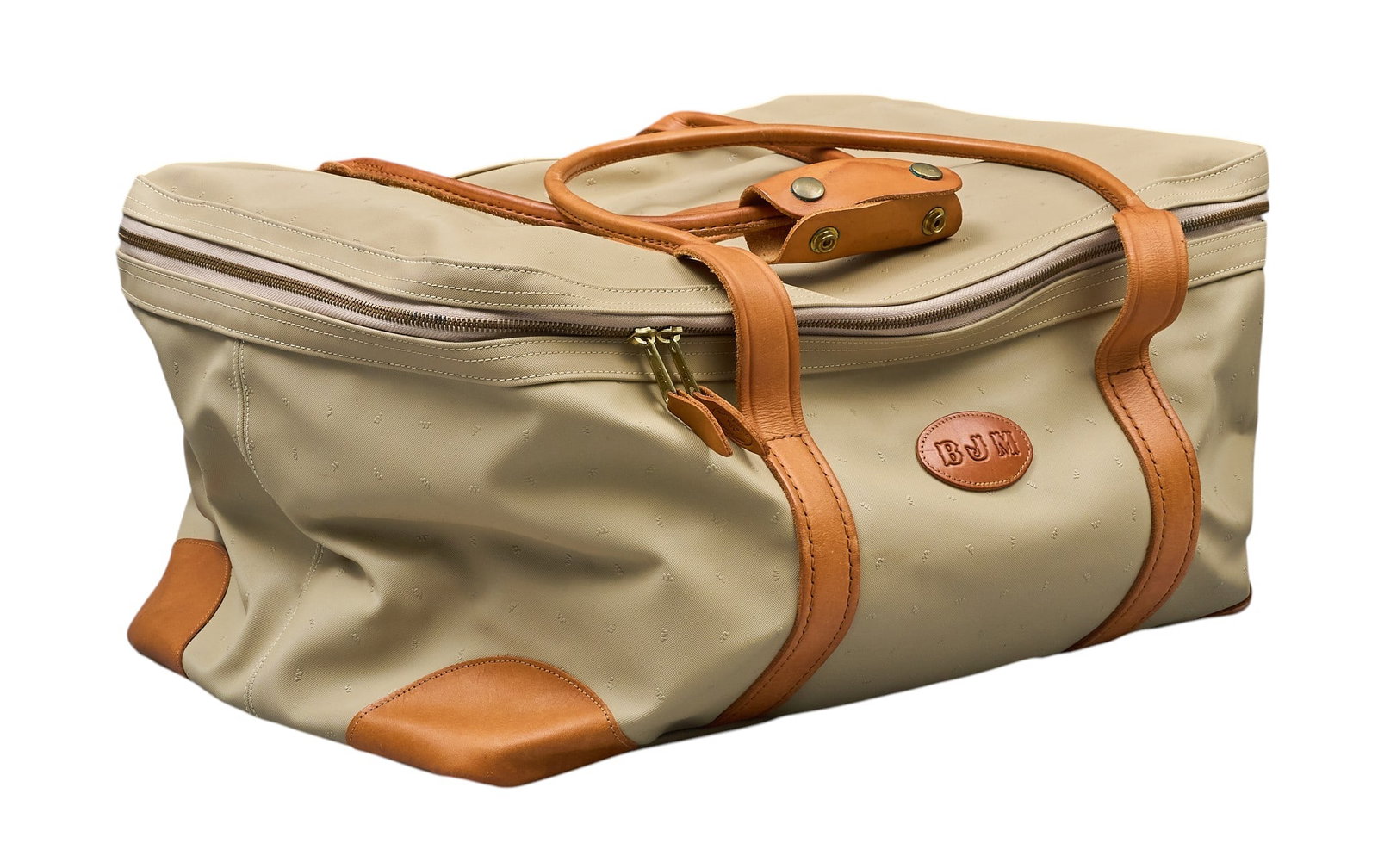 Red McCombs | King Ranch Travel Bag: King Ranch monogram canvas travel bag with brown leather handles, and "BJM" label height 10 in. x width 12.5 in. x depth 21 in. Condition A; excellent condition, shows little signs of 