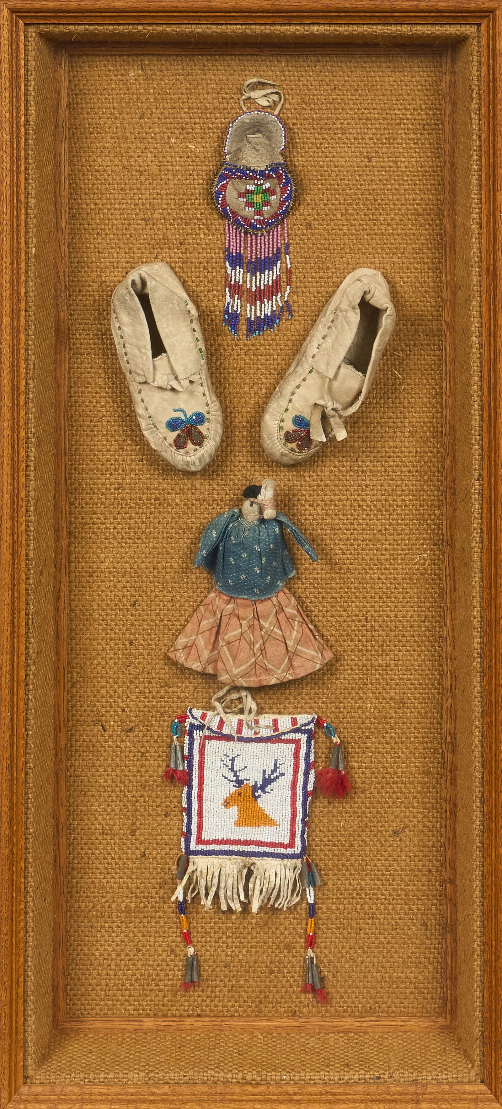 Red McCombs | Framed Native American Items: Framed collection of Native American items, includes two beaded pouches, a pair of moccasins, and a fabric doll height 34 in. x width 15 in. x depth 3.25 in. Provenance: Property from the person