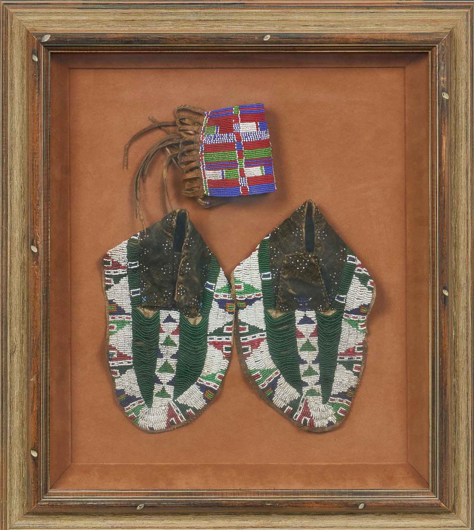 Red McCombs | Framed Beaded Native American Items: Framed collection of hand-beaded Native American items, includes pair of moccasins, and wrist cuff height 23.5 in. x width 21 in. x depth 3 in. Provenance: Property from the personal estate coll