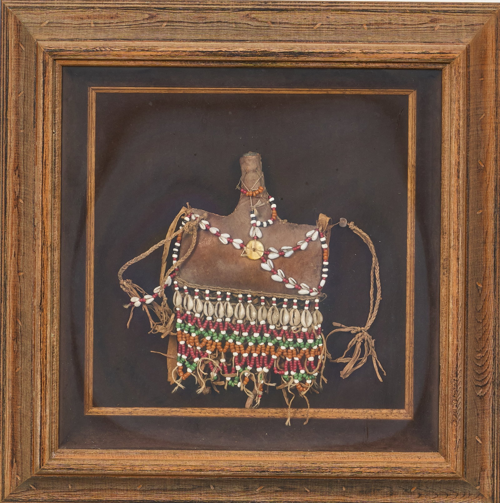 Red McCombs | Framed Native American Canteen: Framed Native American canteen, decorated with deerskin, beads, and cowrie shells height 18 in. x width 18 in. x depth 2.5 in. Provenance: Property from the personal estate collection of iconic 