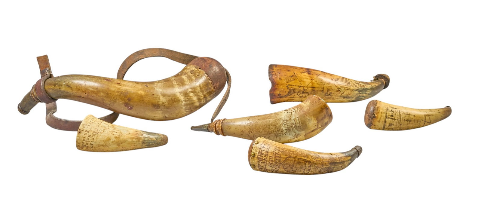 Red McCombs | (6) Antique Powder Horns: Collection of six antique powder horns, some featuring featuring hand-carved decoration, including one with scrimshaw inscribing depicting an attack on a Spanish fortification by British naval vessels