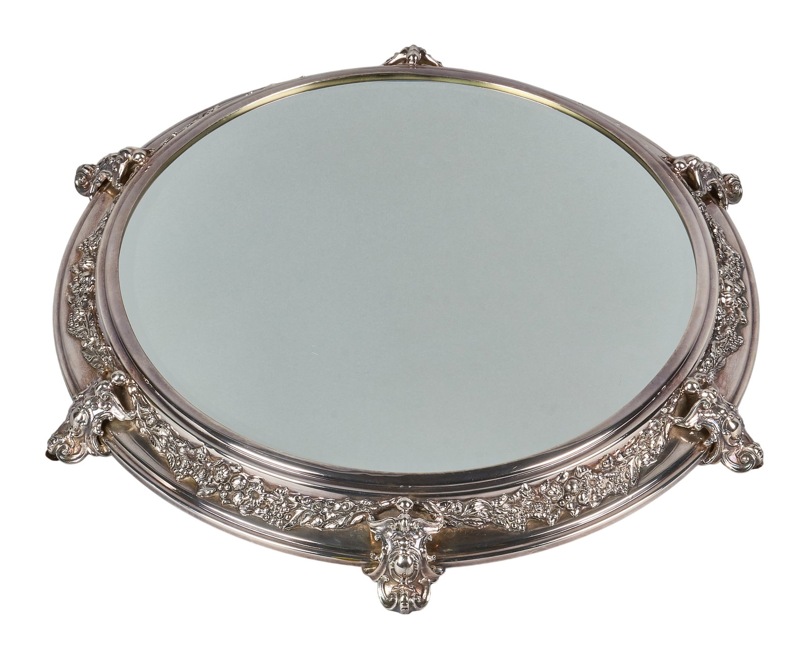 Red McCombs | Silverplate Plateau Mirror: Silverplate mirrored plateau, featuring applied repousse design with foliate motifs, raised on scrolled feet height 2 in. x diameter 20 in.