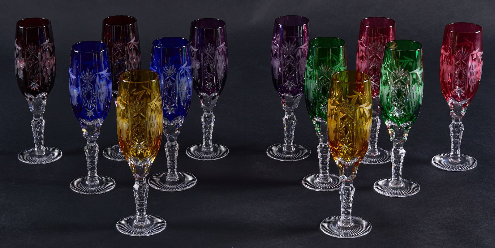 Red McCombs | Collection of (12) Cut-to-Clear Ajka Crystal Marsala Champagne Flutes: Collection of twelve cut-to-clear Ajka Crystal "Marsala" pattern champagne flutes, in various colors height 8 in. Provenance: Property from the personal estate collection of iconic Texa