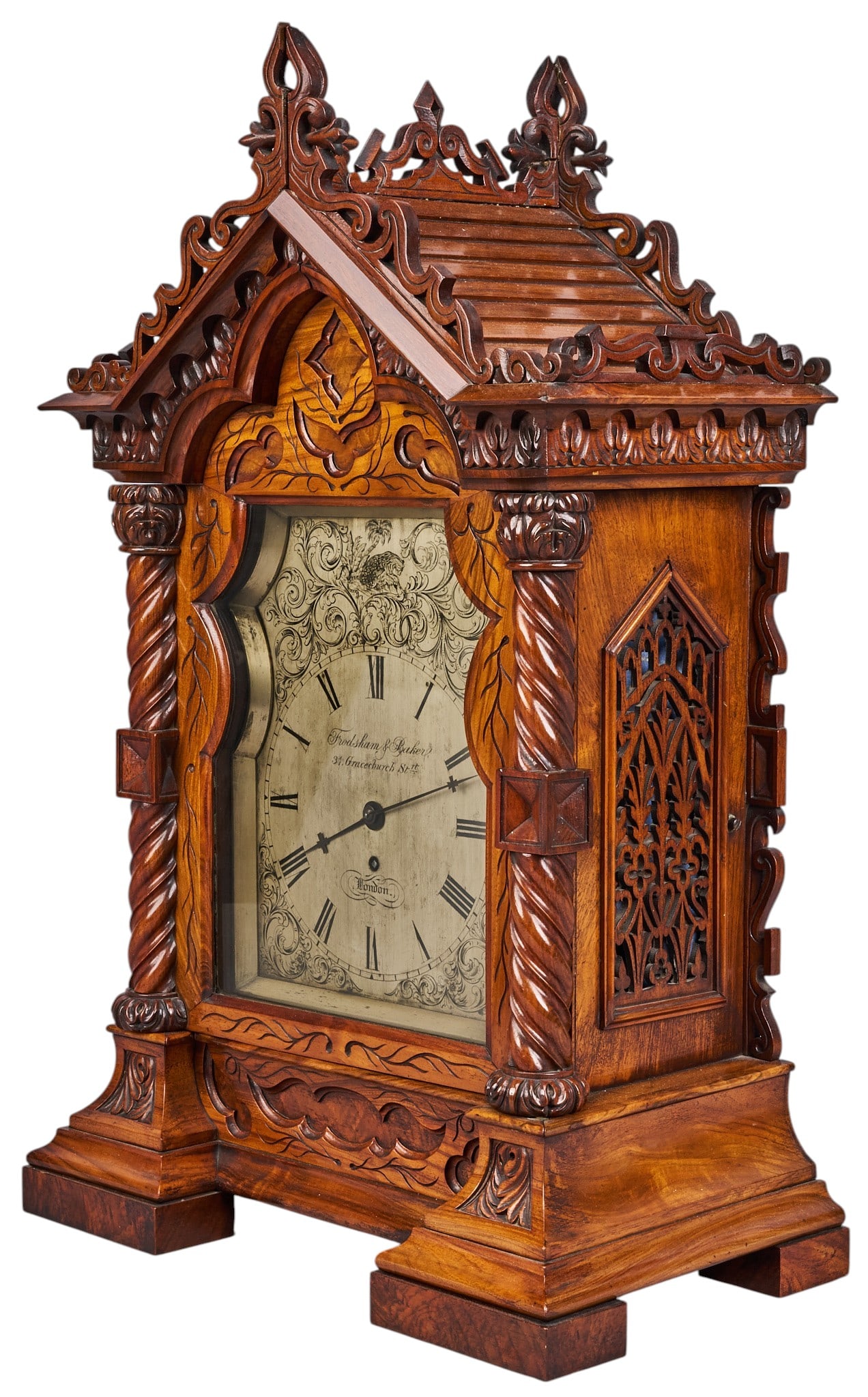 Red McCombs | Frodsham & Baker Mantel Clock: Substantial English Gothic Revival cathedral form bracket clock by Frodsham & Baker (London), with decoratively carved mahogany case, engraved silvered dial with Roman