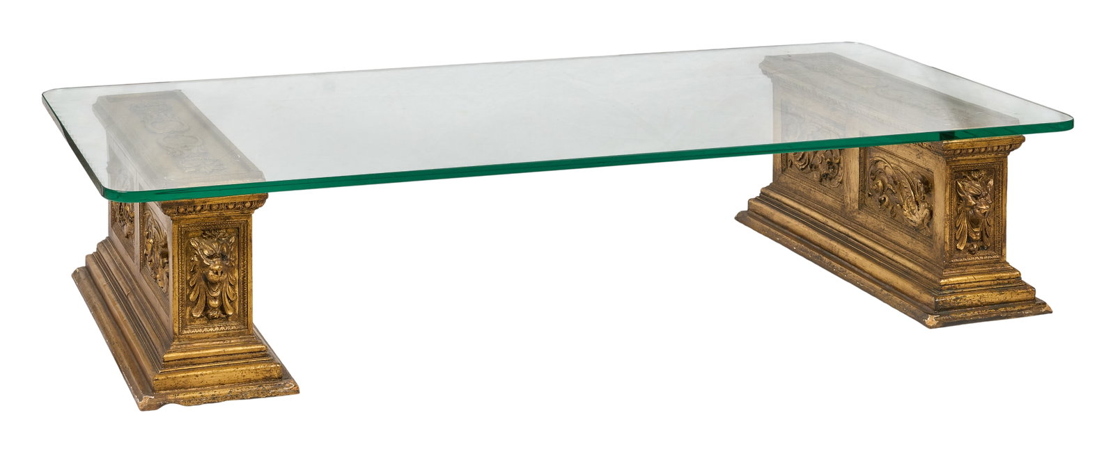 Red McCombs | Renaissance Revival Style Coffee Table: Glass top coffee table supported by two Renaissance Revival style painted plaster plinths with gold finish and carved classical motifs height 15 in. x width 72 in. x depth 36 in. Provenance: Property