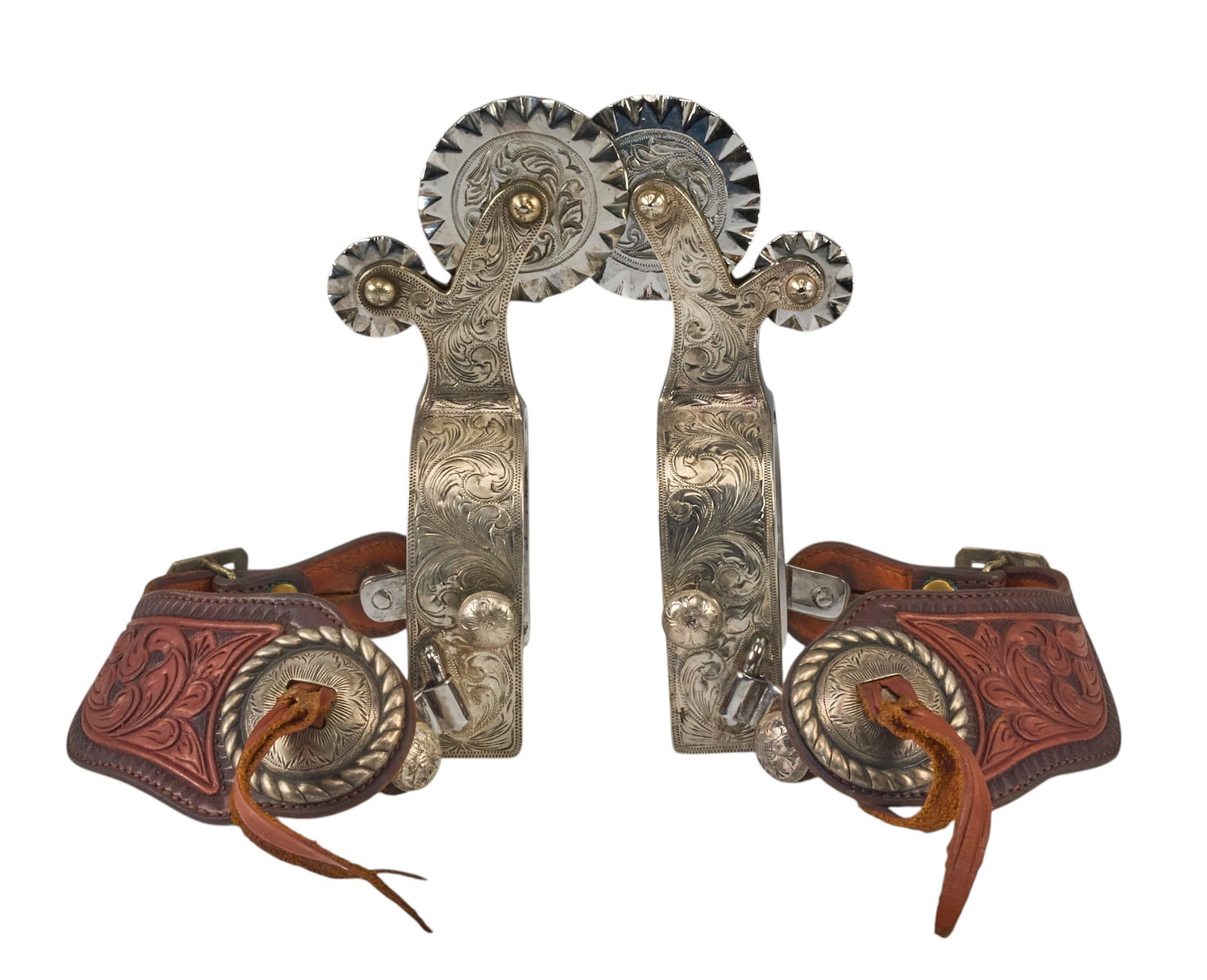 Pair of Tom Mix Pattern Parade Spurs: Exceptional Tom Mix pattern parade spurs, in Bohlin style, intricately carved floral heel band, tooled leather heel straps, floral motif conchos, graduated rowels overall length: 7 in. 