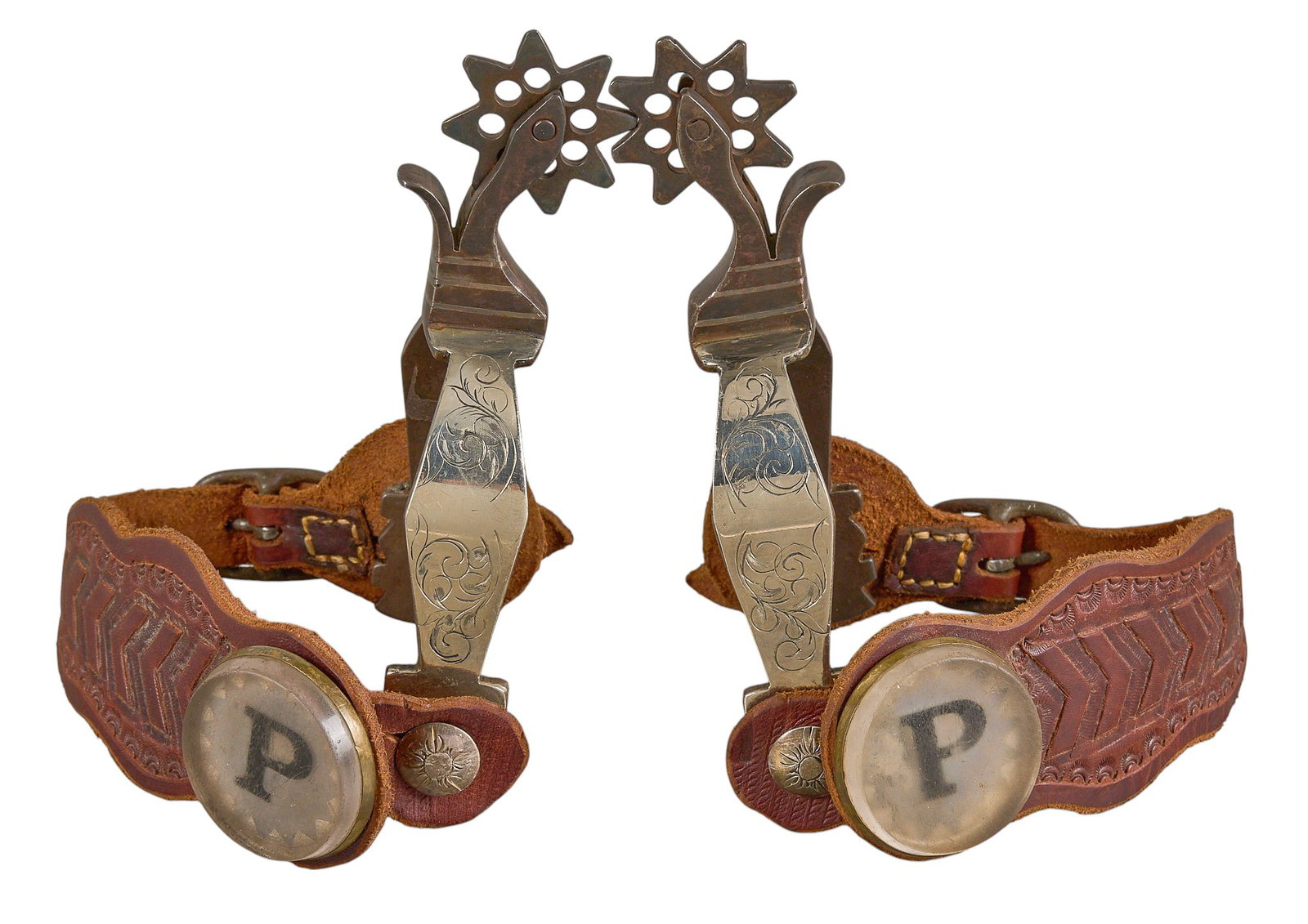 Pair of JH Marked Spurs: Pair of JH maker marked spurs, with silver inlay and overlay, tooled leather heel strap, and P initial button overall length: 7 in heel width: 3 in. rowel diameter: 1.75 in. Provenance: Pr
