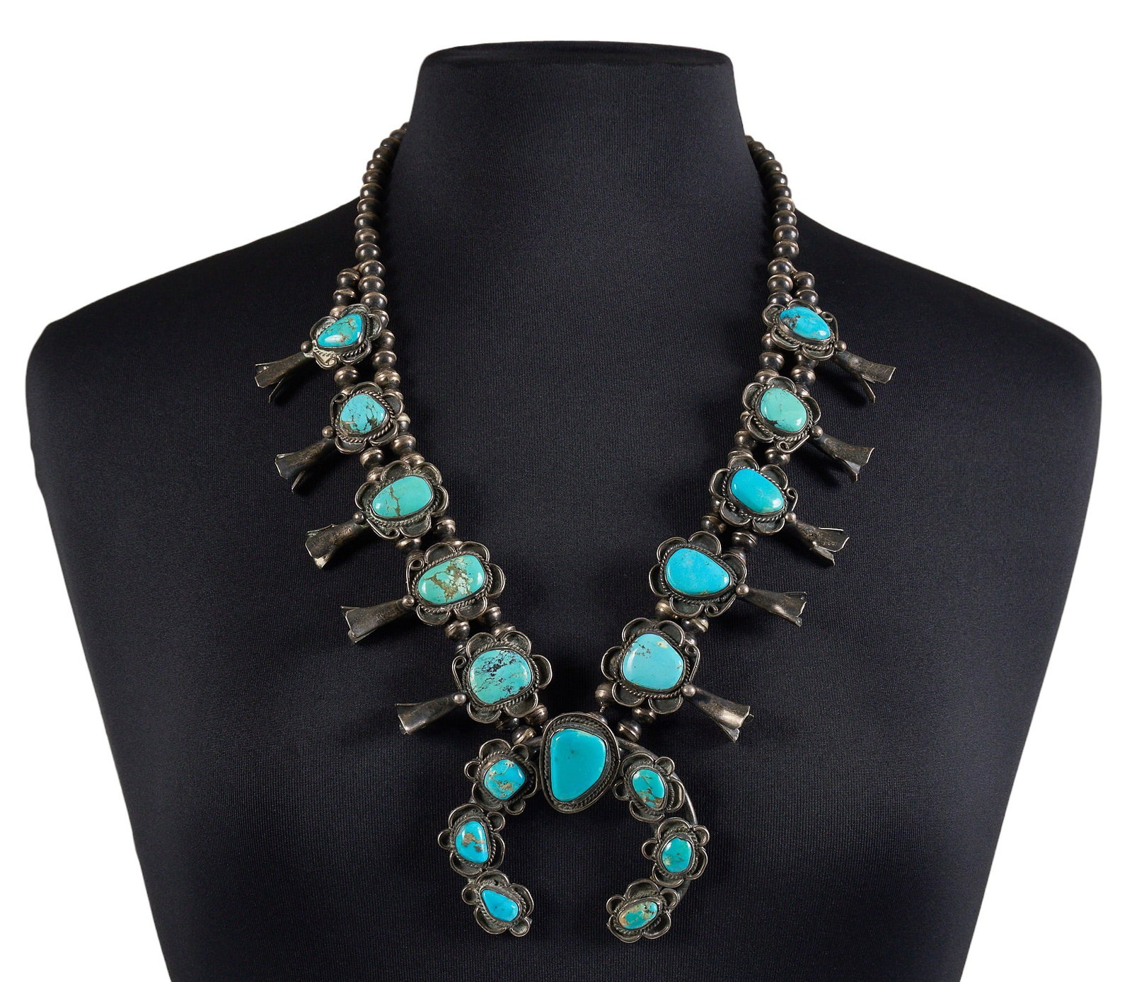 Vintage Sterling & Turquoise Squash Blossom: Vintage sterling silver squash blossom necklace, set with turquois cabochons in twisted wire style settings, with floral scrollwork throughout, and hook and eye closure, circa 1970s Length: 27 in