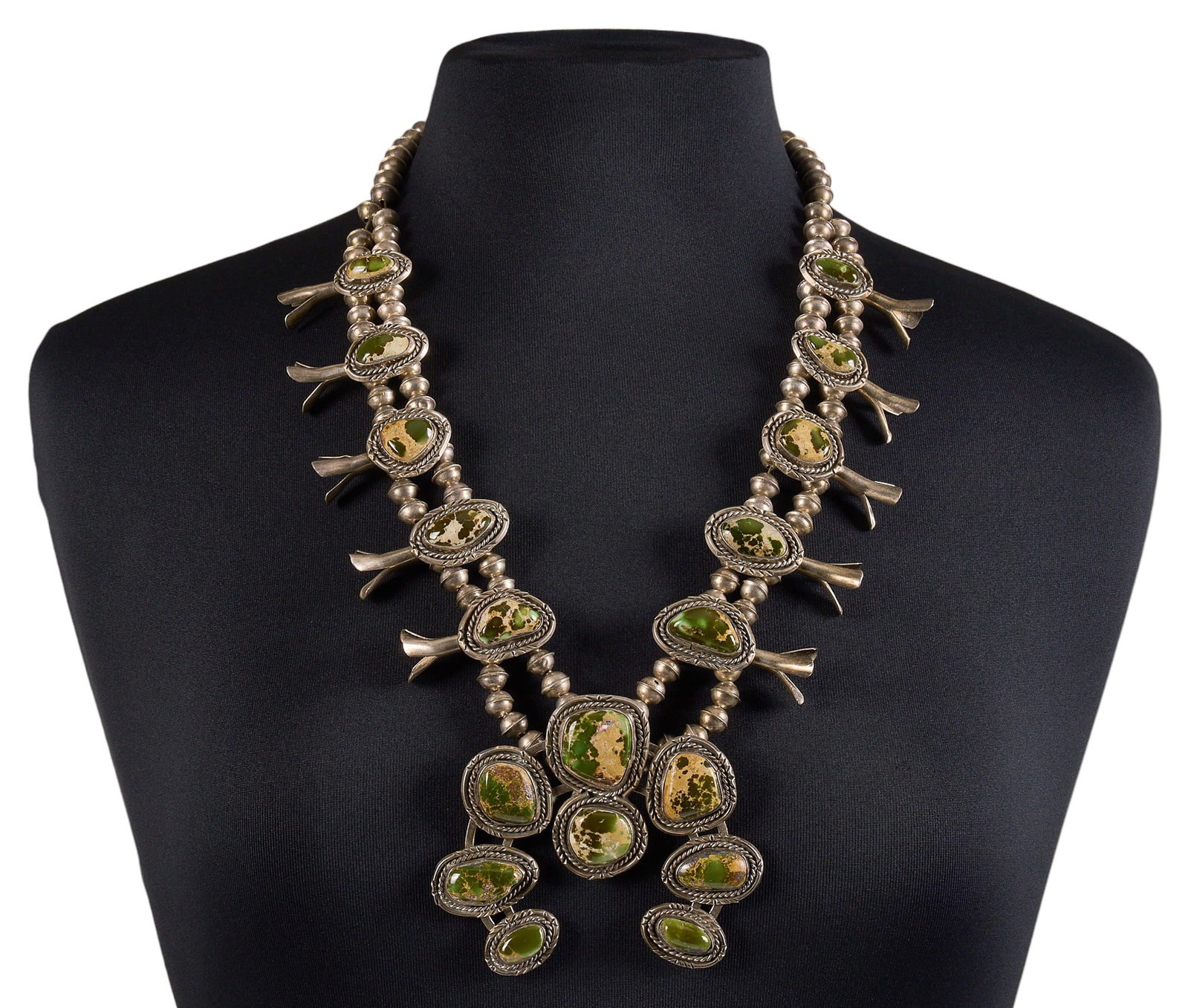 Sterling & Green Turquoise Squash Blossom: Sterling silver squash blossom necklace set with green turquoise cabochons in twisted wire style settings, with hook and eye closure Length: 29 in. Total weight: 219.1 g Provenance: Property from