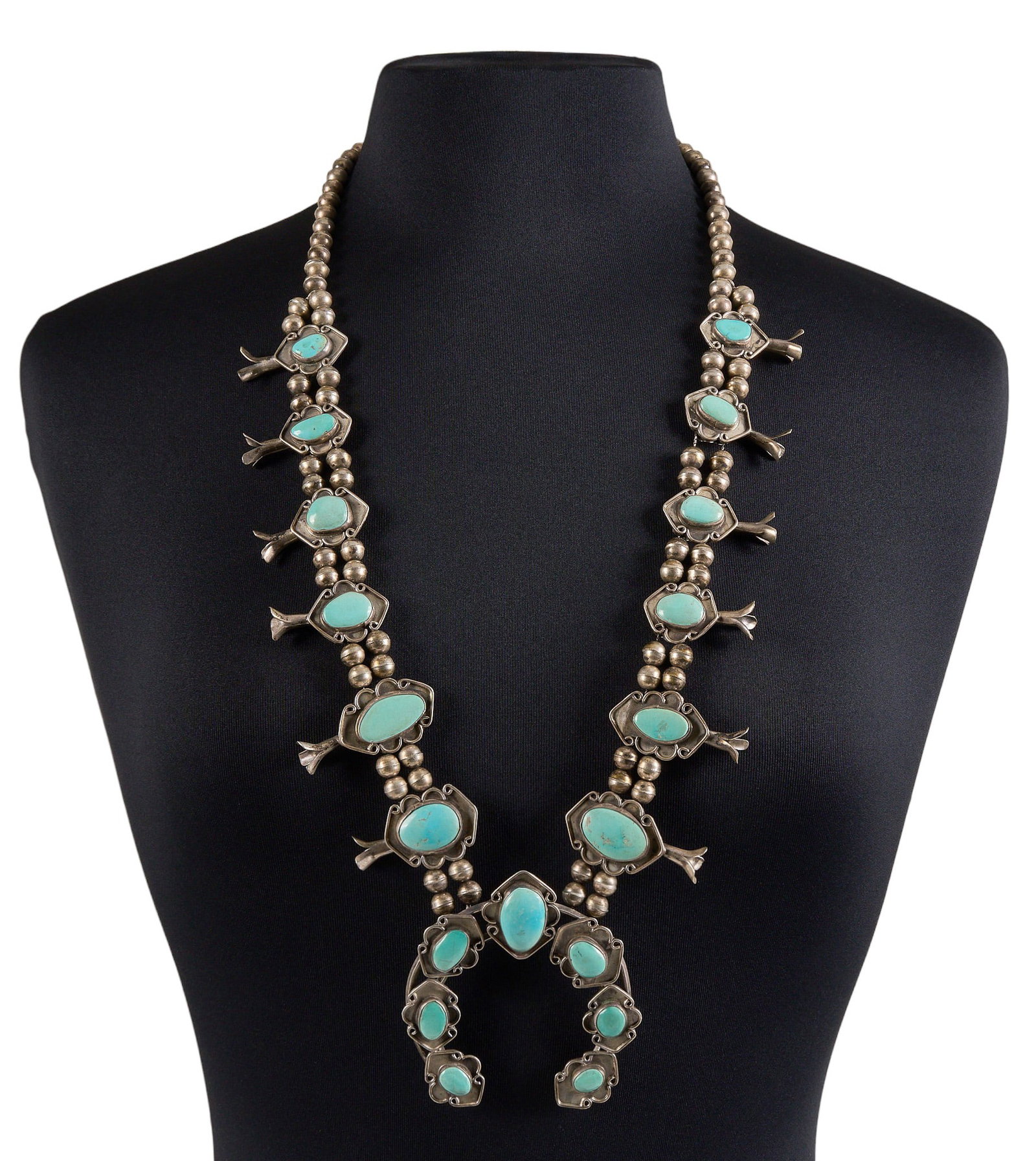 Vintage Navajo Sterling & Turquoise Squash Blossom: Vintage Navajo sterling silver squash blossom necklace, set with graduated turquoise cabochons, scrolled details, and hook and eye closure Length: 33.5 in. Total weight: 182.0 g Provenance: 