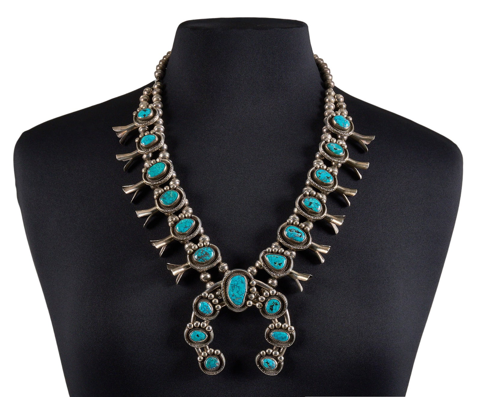 Sterling Silver & Turquoise Squash Blossom: Sterling silver squash blossom necklace, set with turquoise cabochons and twisted wire motifs, featuring hand-stamped details, with hook and eye closure Length: 26 in. Total weight: 286.7 g Prove