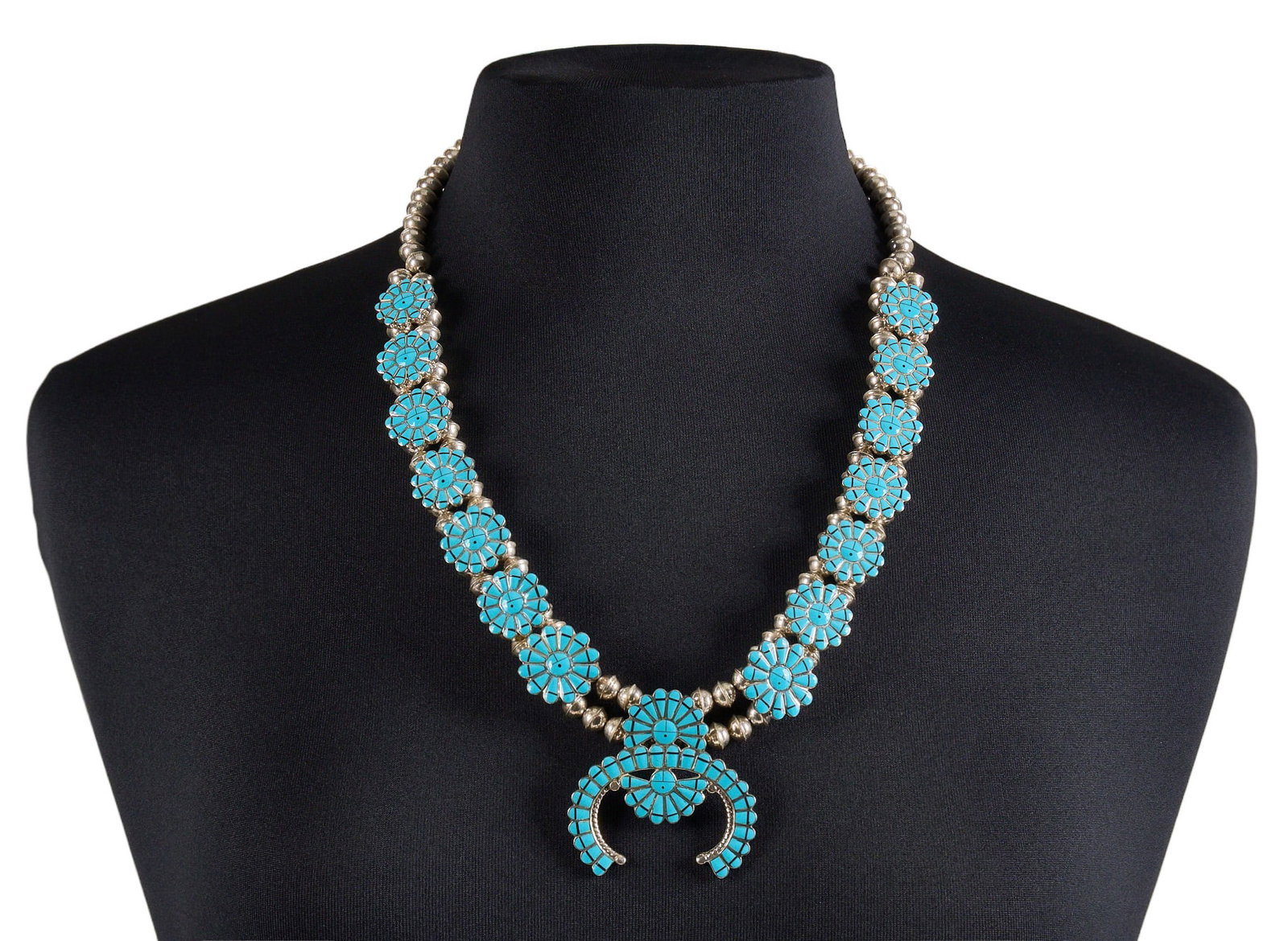 Navajo Sterling & Turquoise Inlay Squash Blossom: Navajo sterling silver squash blossom necklace, set with turquoise inlay in floral design, with hook and eye closure, signed "NG" to naja Length: 24 in. Total weight: 102.5 g Prove