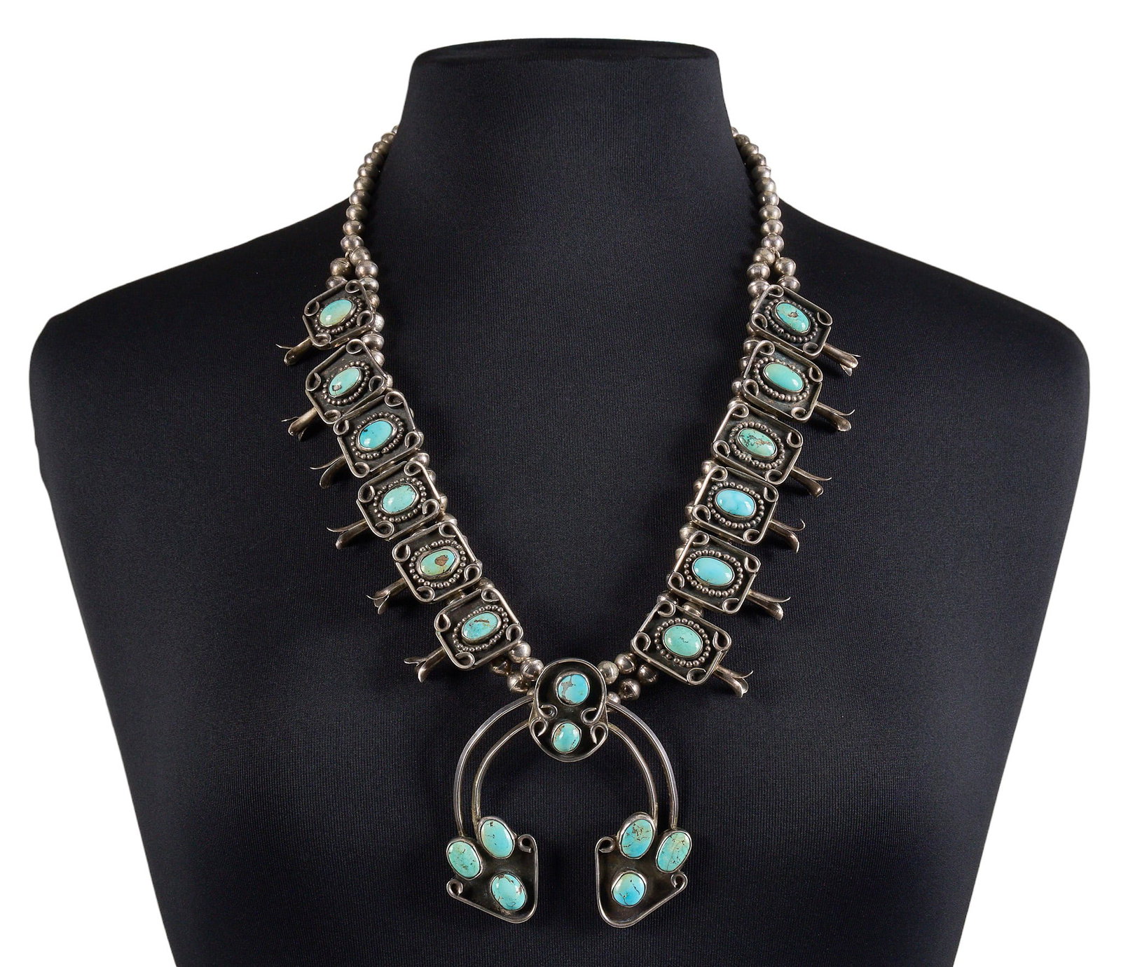 Sterling & Turquoise Squash Blossom: Sterling silver squash blossom necklace set with round turquoise cabochons in textured settings, with hook and eye closure Length: 26 in. Total weight: 215.7 g Provenance: Property from a home in