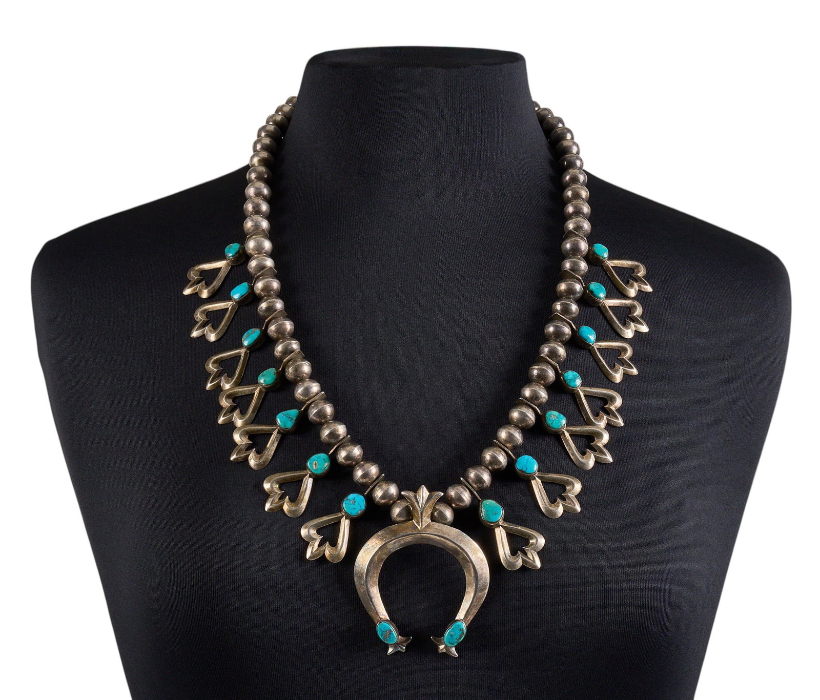 Sterling Silver & Turquoise Squash Blossom: Sterling silver squash blossom necklace set with turquoise cabochons, with hook and eye closure Length: 27 in. Total weight: 217.7 g Provenance: Property from a home in San Antonio, Texas