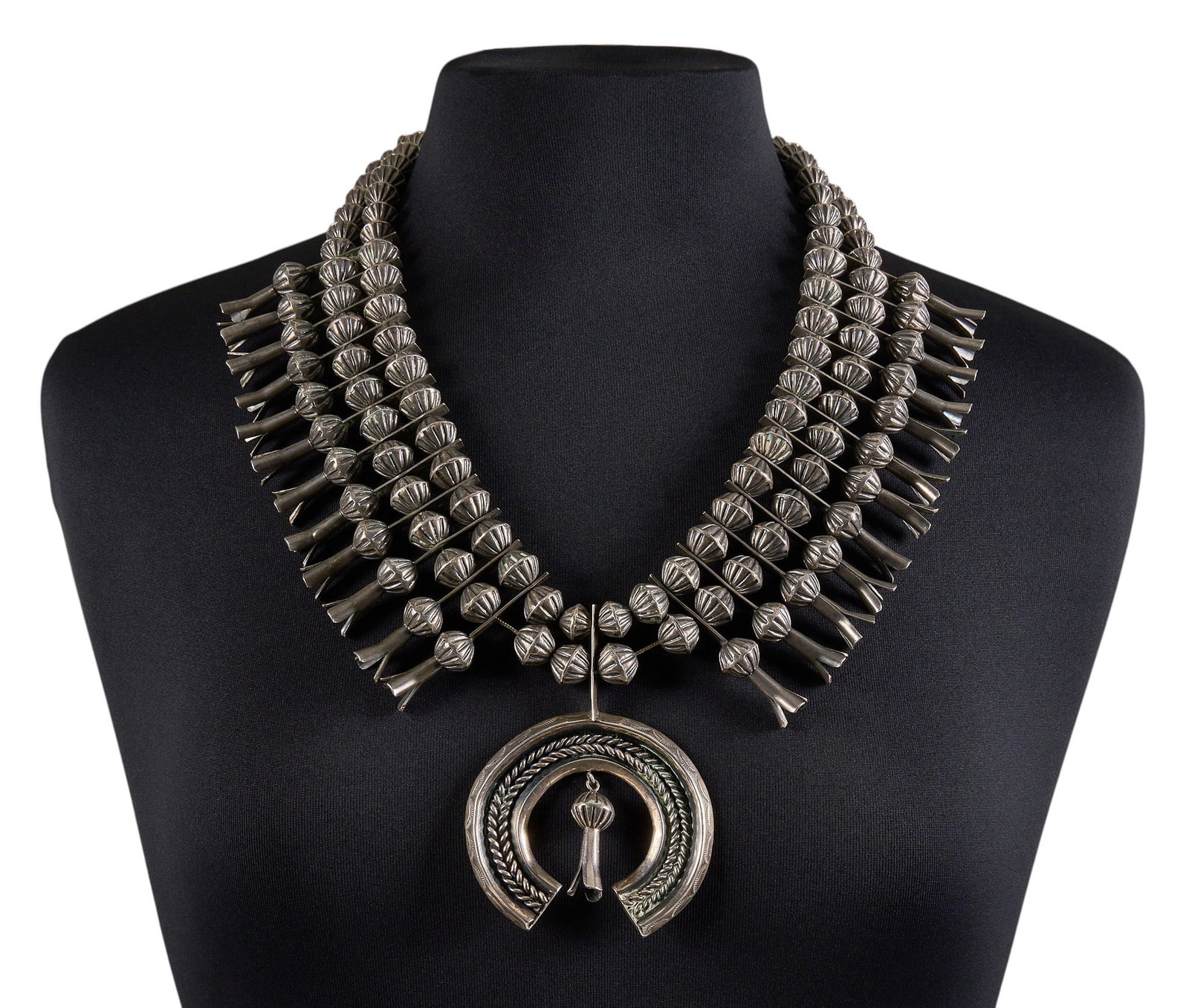 Sterling Silver Squash Blossom: Sterling silver squash blossom necklace, with hand-stamped beads and twisted wire motif to naja, hook and eye closure Length: 24 in. Total weight: 365.9 g Provenance: Property from a home in San Anton