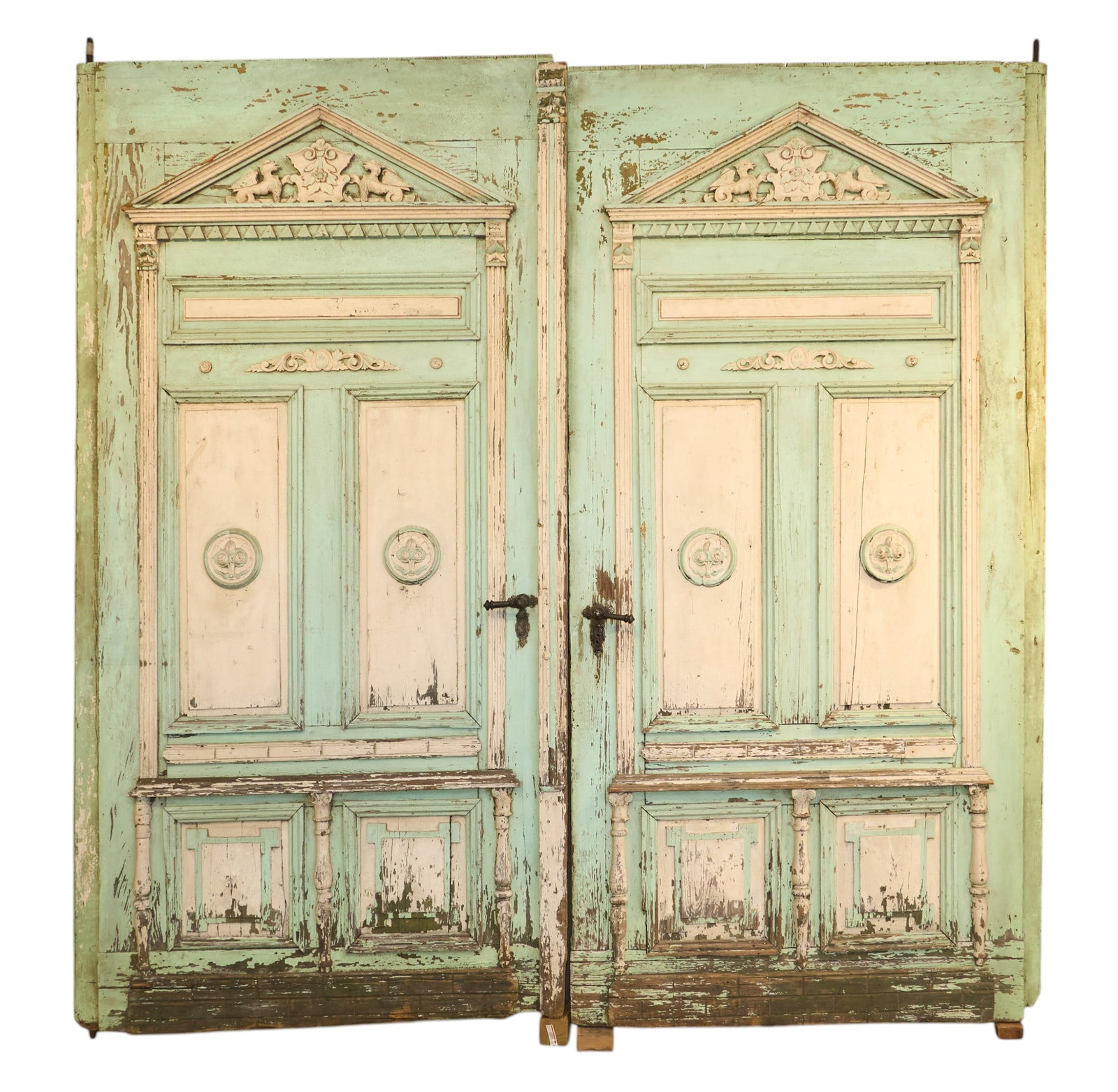 Pair of Monumental Architectural Doors: Pair of monumental weathered wooden double doors decorated with carved pediments, and medallions, with distressed light blue and white paint height 120 in. x width 58 in. x depth 5 in. / each