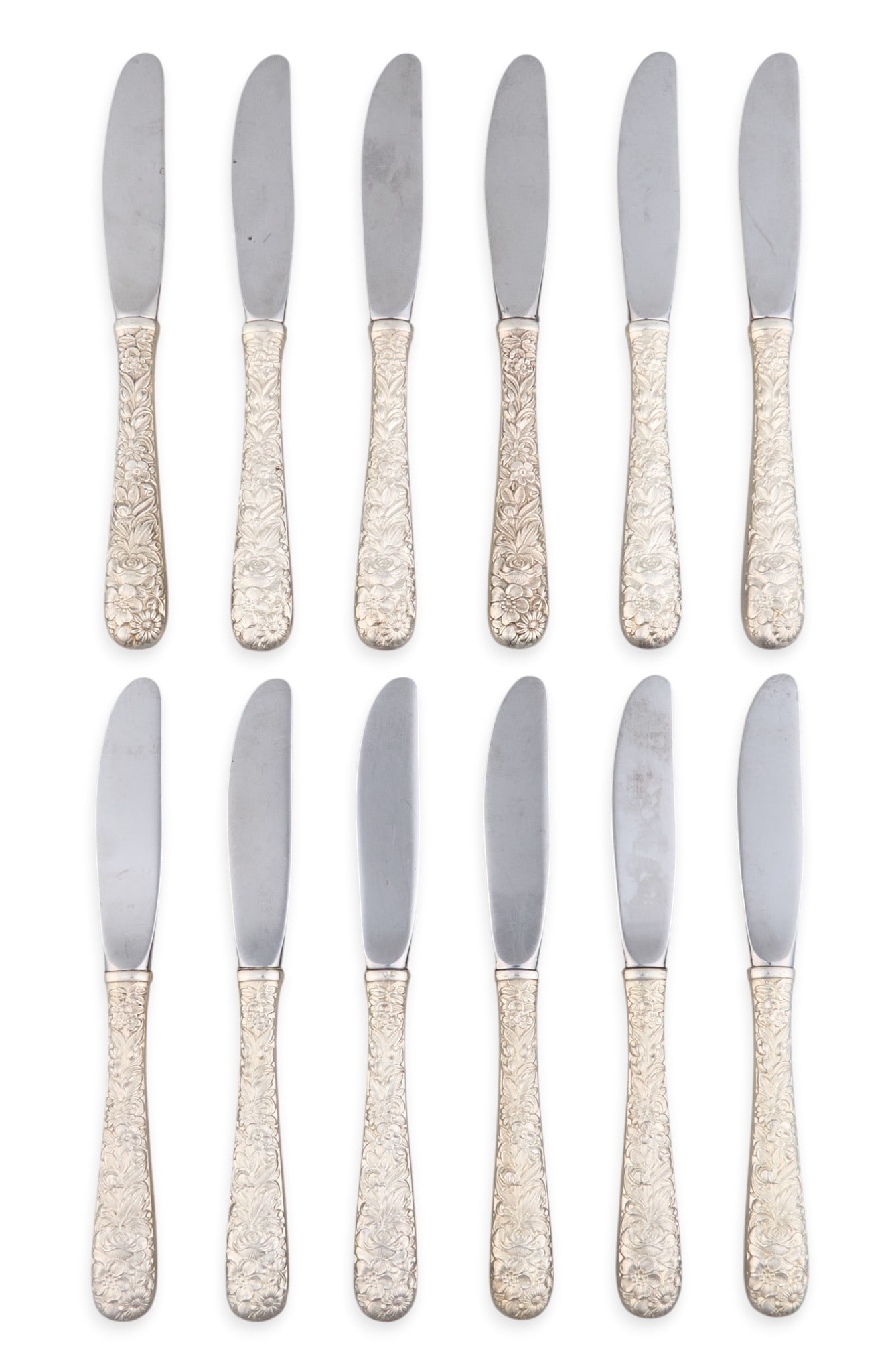 (12) Sterling Silver Repousse Butter Knives: Twelve sterling silver repousse butter knives length: 6 in. Total weight: 3.00 ozt (weighable silver) Provenance: Property from the collection of an industrial chemicals entrepreneur, from his A