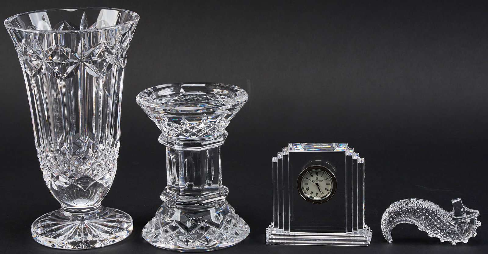 Waterford Crystal Desk Suite: Waterford crystal desk suite, to include a footed vase, candle pedestal, desk clock, and seahorse hand-cooler, all marked Waterford height 8.5 in. x 5 in. diameter / vase Provenance: Property from a h