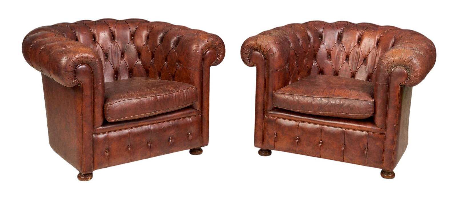 Pair of Tufted Club Chairs: Pair of Chesterfield style club chairs in tufted reddish brown leather, supported on wooden bun feet height 28.5 in. x width 42 in. x depth 33 in. / each 