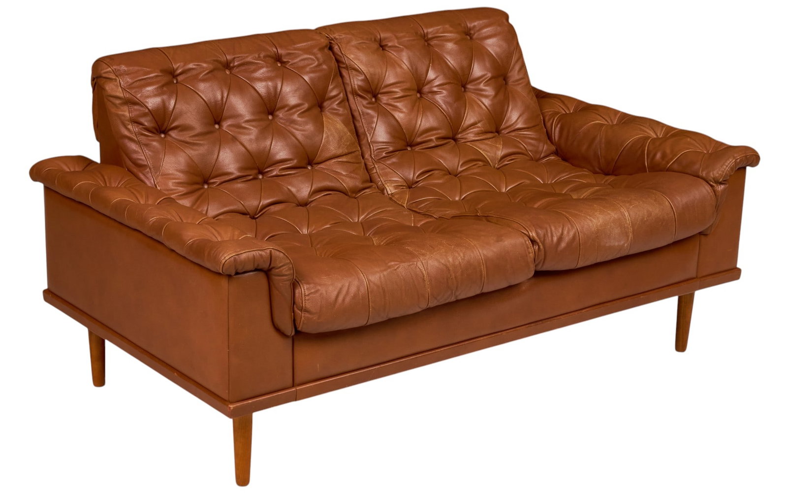 Danish Mid-Century Tufted Leather Loveseat: Danish mid-century two-seat loveseat, caramel brown leather upholstery with deep button tufting, loose tufted seat and back cushions, rolled padded arms, raised on tapered wood legs height 31 in. x
