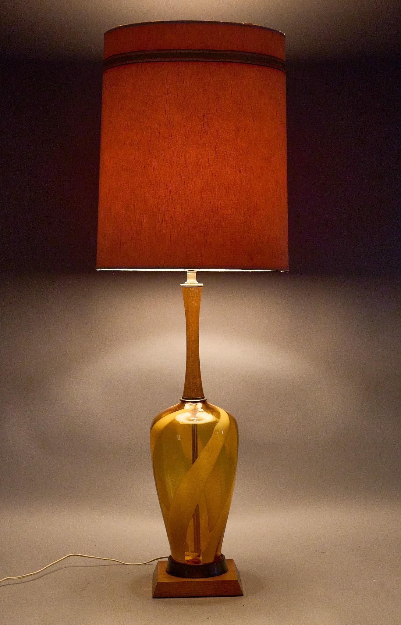 Mid-Century Art Glass Table Lamp: Vintage mid-century amber swirl art glass table lamp featuring a striking internal ribbon design and a wooden base, includes cylindrical shade, circa late 1960s height 43 in. x width 15 in. x de