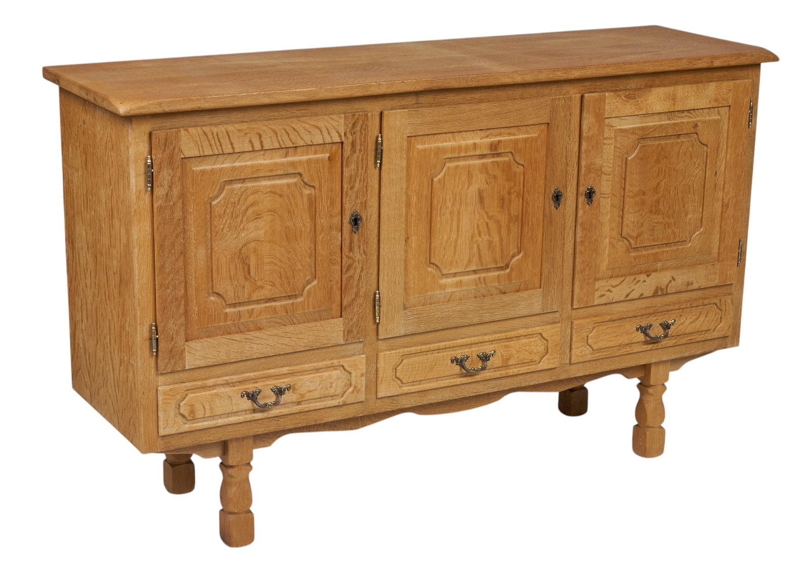 Henning Kjaernulf, Mid-Century Credenza: Henning Kjaernulf (Denmark) oak mid-century credenza with three carved cabinet doors, decorated with brass escucheon, that open to three separate shelved interiors above three drawers with decorative
