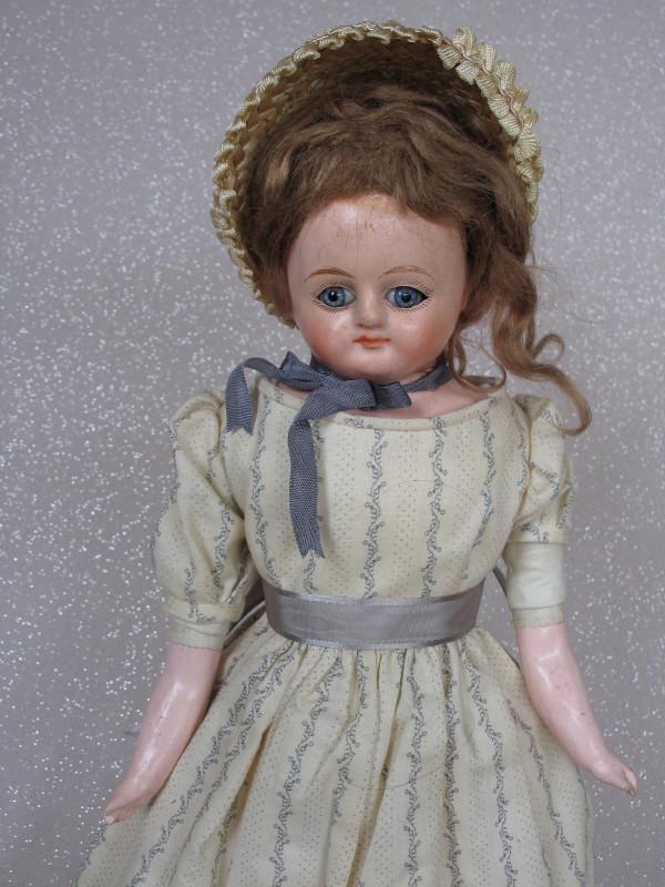 Turned F. M. Schilling shoulderhead 38cm 1900s.: Turned F. M. Schilling shoulderhead 38cm 1900s. Papier-Mache composition, full length chip on back plate rim. Inserted blue glass eyes, one loose. Cloth original body and lower composition limbs with