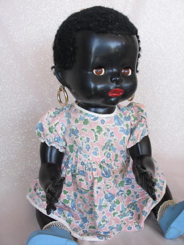English Pedigree 1953 'Mandy Lou' baby 19" (48cm) .: English Pedigree 1953 'Mandy Lou' baby 19" (48cm) . Black hard plastic, brown flirty/sleep eyes, real lashes, open closed red accentuated mouth, gold hoop earrings, astrakhan wig with a pink bow . All