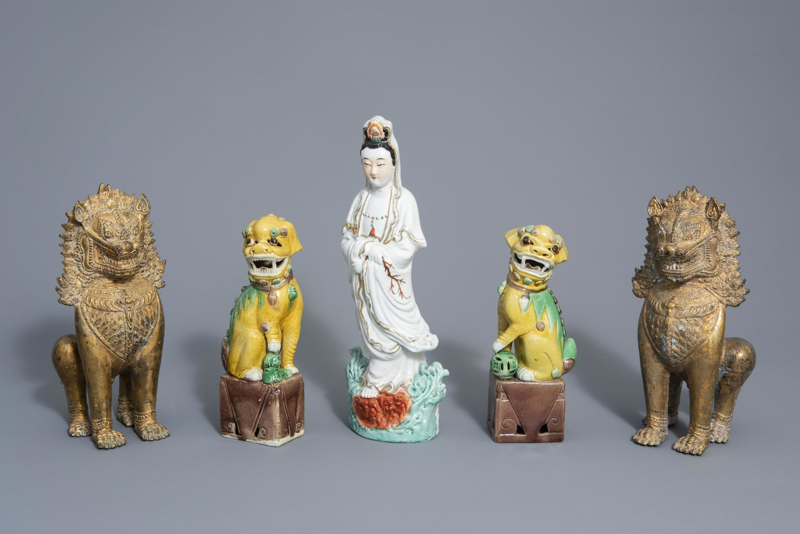 A Chinese porcelain Guanyin, a pair of sancai Buddhist: A Chinese porcelain Guanyin, a pair of sancai Buddhist lions and a pair of Thai gilt bronze lions, 19th/20th C. H 34,5 cm (the Guanyin)Â H 23 cm (the pair of sancai lions)