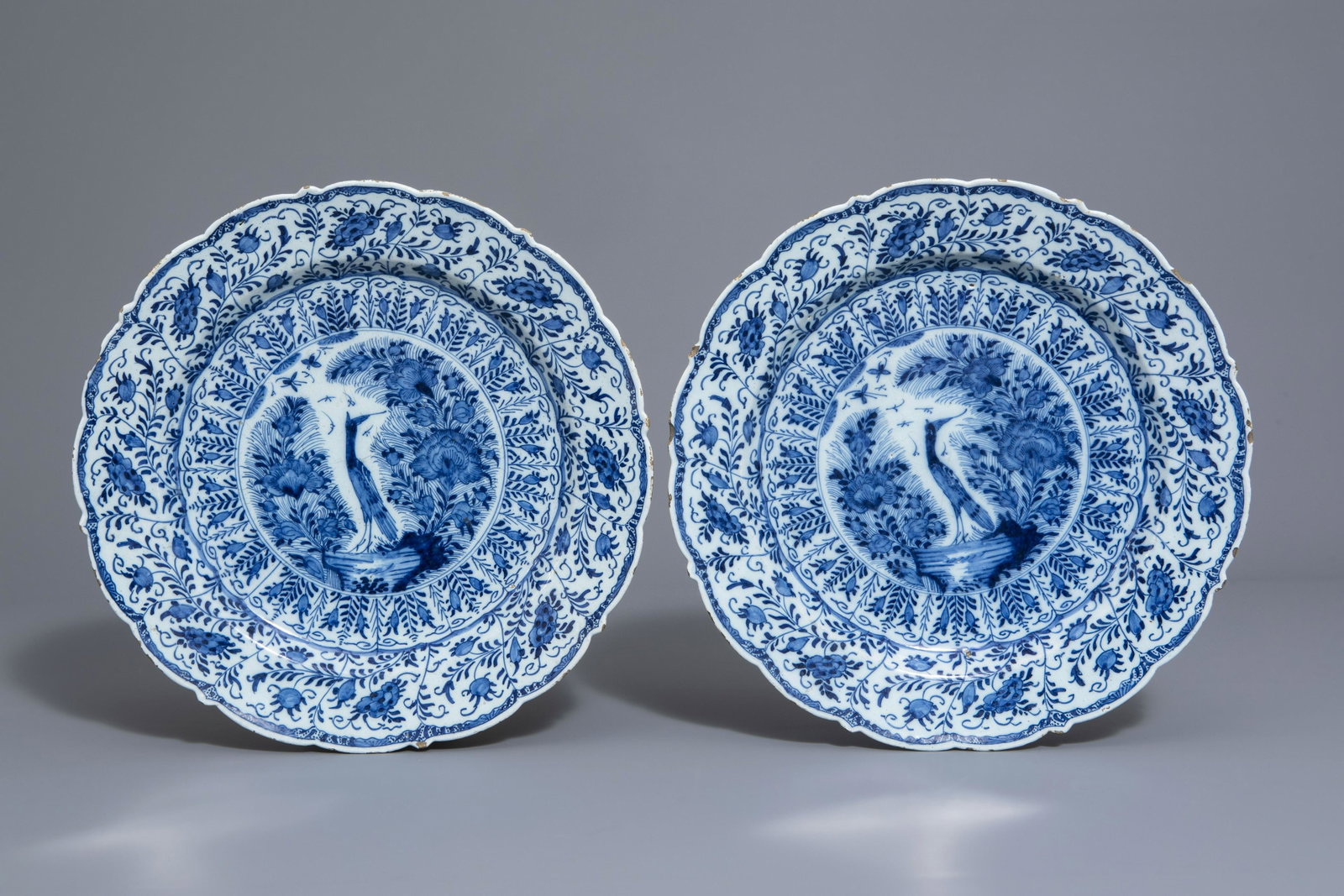 A pair of Dutch Delft blue and white chargers with a: A pair of Dutch Delft blue and white chargers with a bird among blossoming branches, 18th C. Dia.: 34,3 cmÂ Both chargers marked on the base with an axe for the 'De Porceleyne Bijl' workshop, Delft