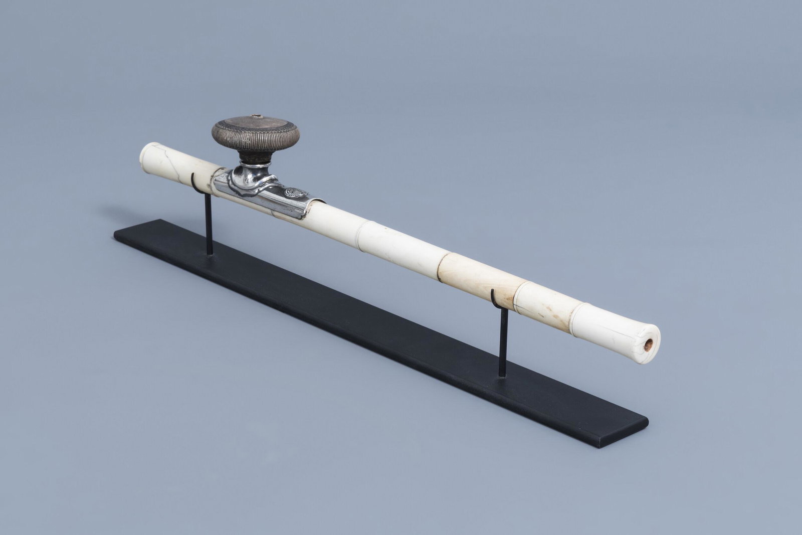 A Chinese opium pipe finished with a silver saddle and: Full title: A Chinese opium pipe finished with a silver saddle and a stoneware damper, 19th C. Description: L 53,9 cm Lot subject to CITES-regulation. Accompanied by a certificate from an external app
