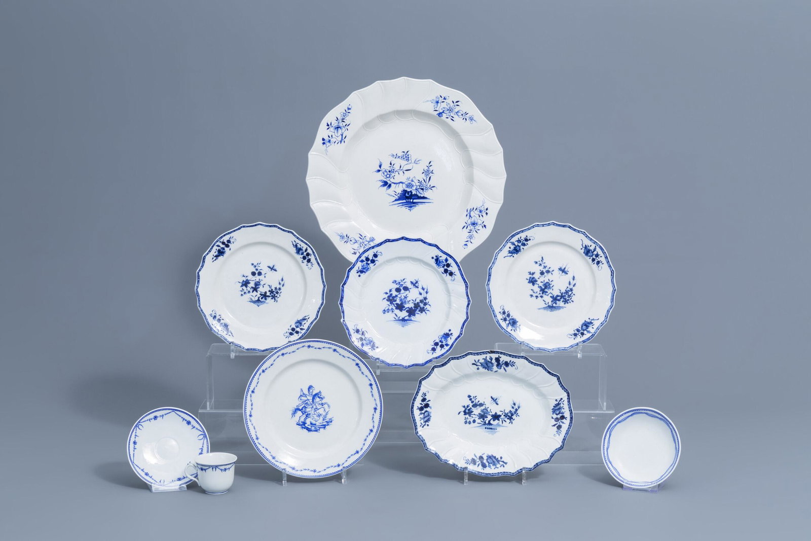 A varied collection of blue and white Tournai: Full title: A varied collection of blue and white Tournai porcelain, 18th/19th C. Description: Dia.: 38,2 cm (the charger) Dia.: 24,3 cm (the plates) Dia.: 14,2 - 13,8 cm (the saucers) H 6 - L 9 cm (t