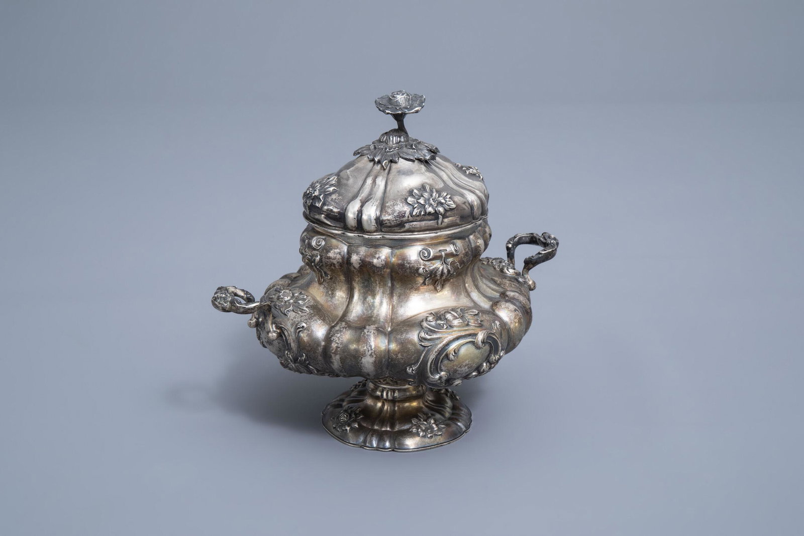A Belgian silver sugar bowl with floral relief design,: Full title: A Belgian silver sugar bowl with floral relief design, maker's mark Wolfers, 833/000, Brussels, 19th C. Description: H 18 - L 21 cm Weight: 510 g The item marked with the Janus head and nu