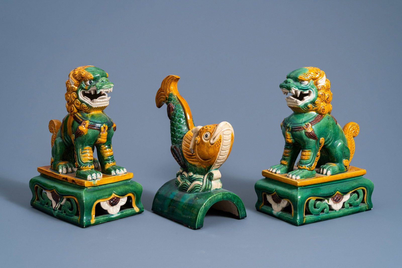 A Chinese sancai fish-form roof tile and two temple: Full title: A Chinese sancai fish-form roof tile and two temple lions, 20th C. Description: H 30,5 - 28,5 cm (the tallest and the smallest item)