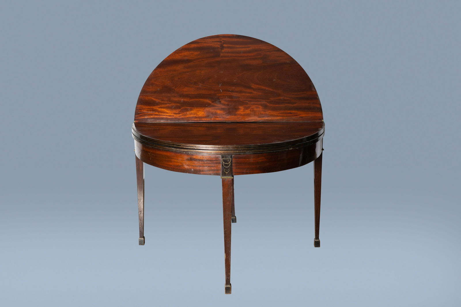 A Belgian mahogany 'demilune' card table with brass: Full title: A Belgian mahogany 'demilune' card table with brass inlay, marked Chapuis (Jean Joseph Chapuis, 1765-1864), early 19th C. Description: H 75,5 - Dia.: 101 cm