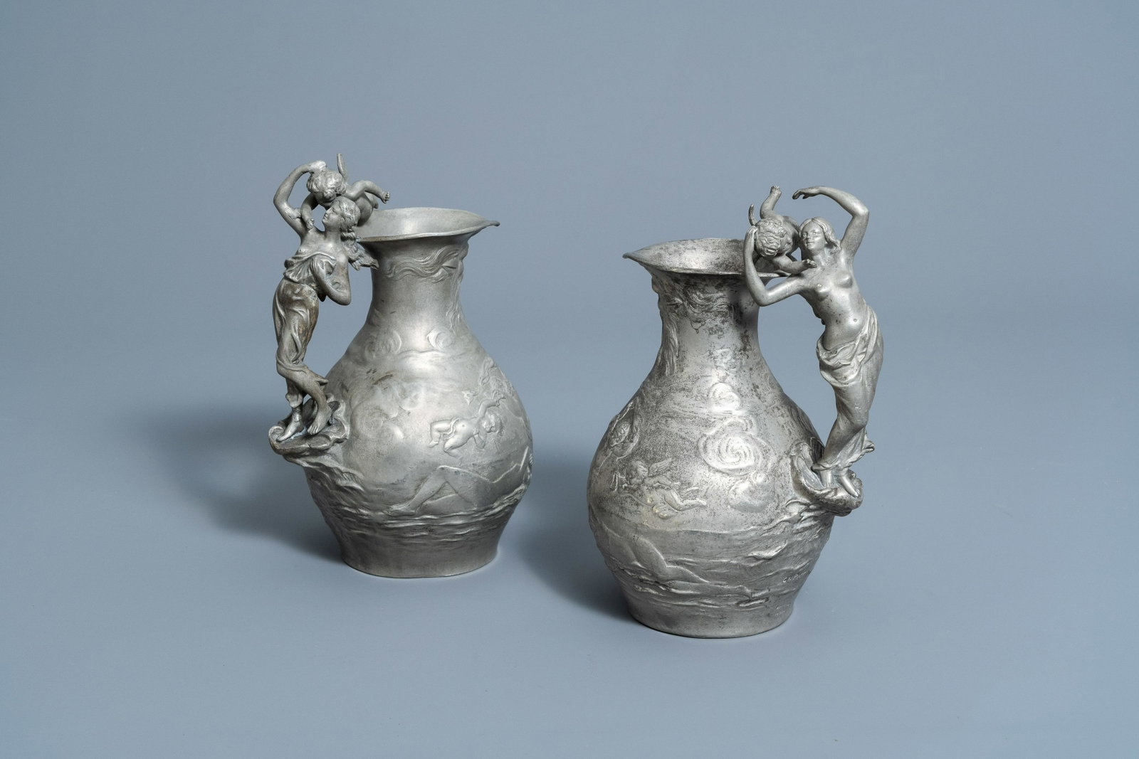 Charles ThÃ©odore Perron (1862-1934): A pair of Art Nouveau pewter 'nymphs and cherubs' pitchers: Full title: Charles ThÃ©odore Perron (1862-1934): A pair of Art Nouveau pewter 'nymphs and cherubs' pitchers with relief design, France, dated 1895 Description: H 24,5 cm Both pitchers marked 'Etain